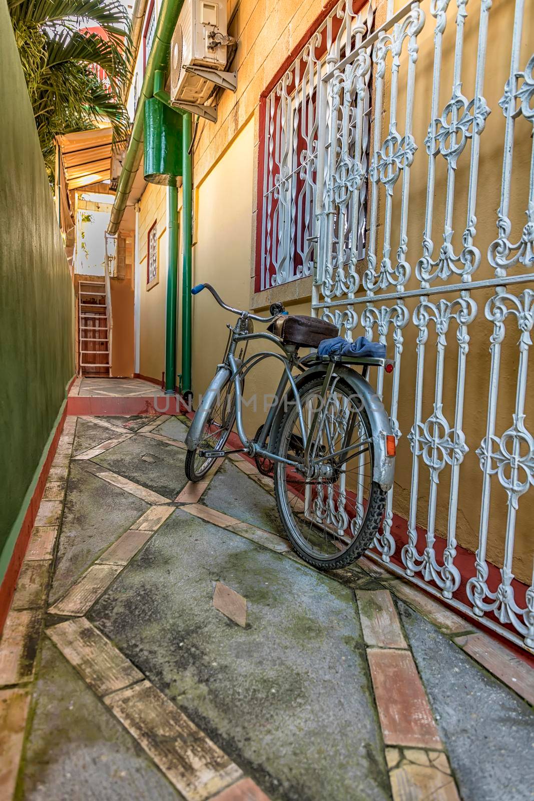 Colorful Old bicycle left at the fence on the house. Vertical view by EdVal