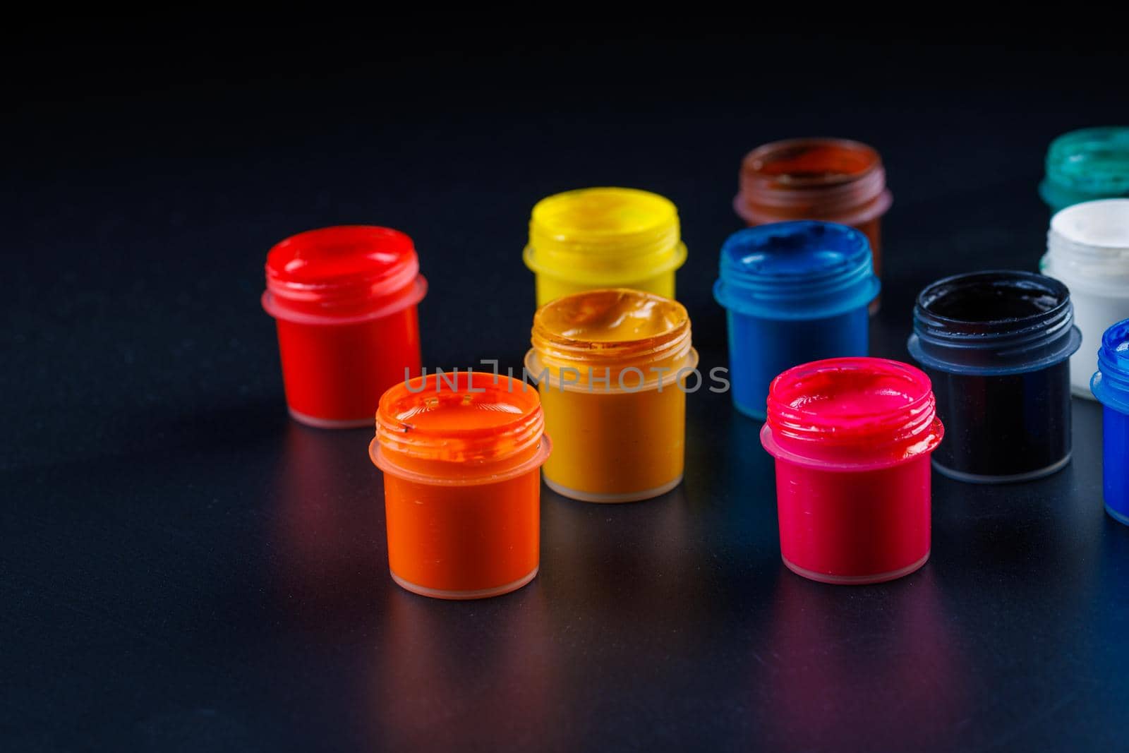 close-up background of opened small gouache paint jars on black surface by z1b