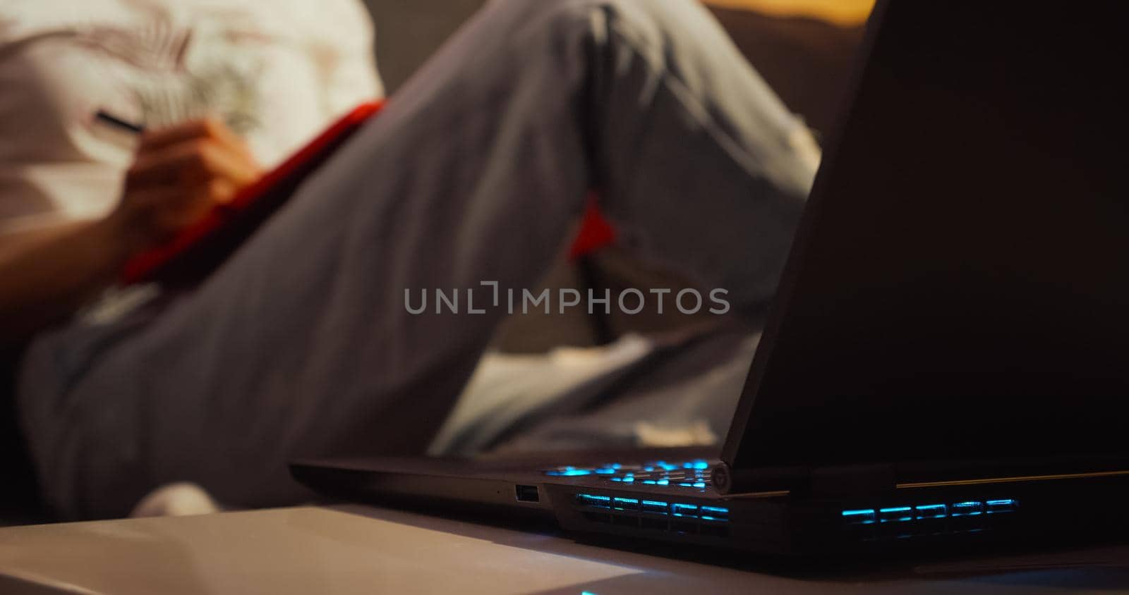 Woman working from home overtime at laptop and makes notes. by RecCameraStock