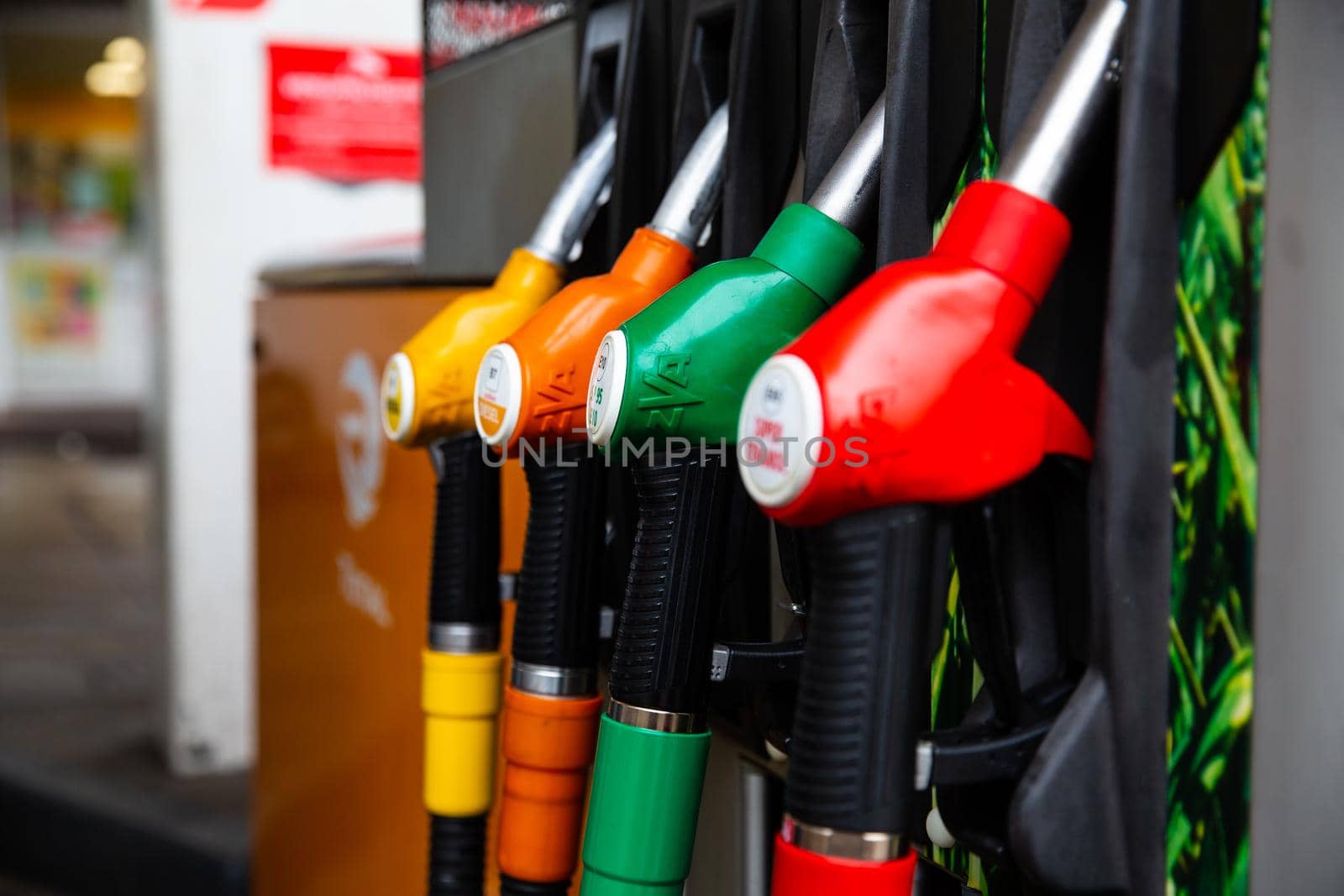 Close up on fuel nozzle in oil dispenser with gasoline and diesel in service gas station. Blue, green, red, golden colors.