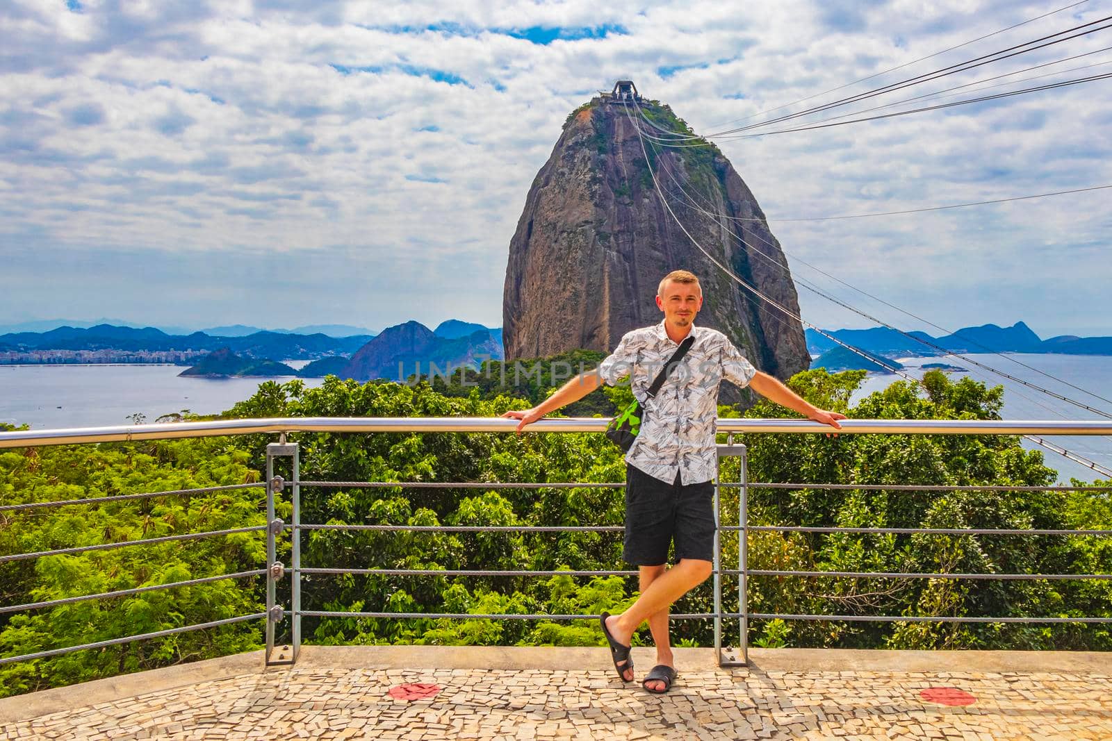 Tourist traveler is posing at the Sugarloaf sugar loaf mountain Pão de Açucar with cable car panorama view in the Urca village in Rio de Janeiro Brazil.