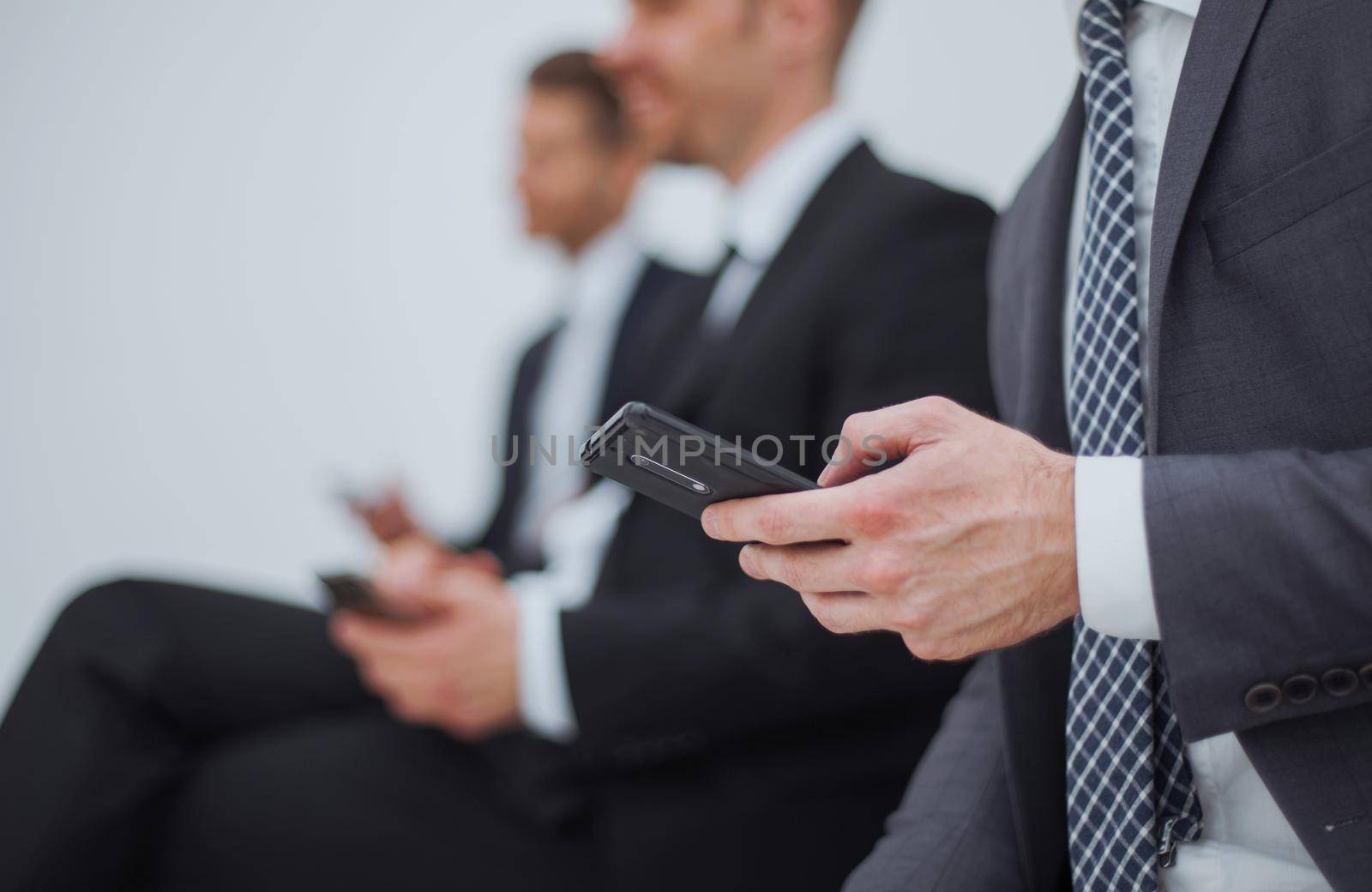 businessman with a smartphone sitting in the office reception by asdf