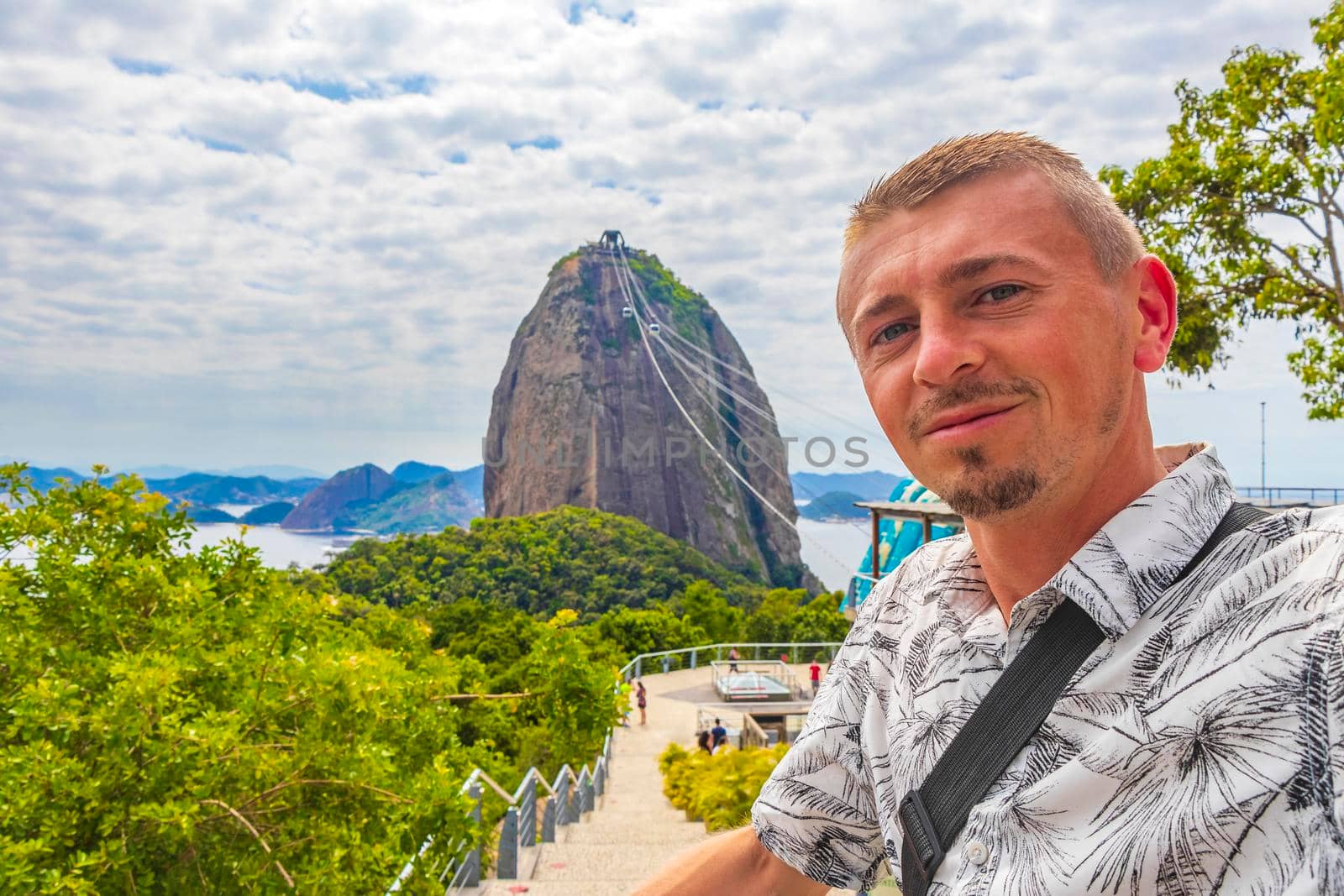 Tourist traveler is posing at the Sugarloaf sugar loaf mountain Pão de Açucar with cable car panorama view in the Urca village in Rio de Janeiro Brazil.