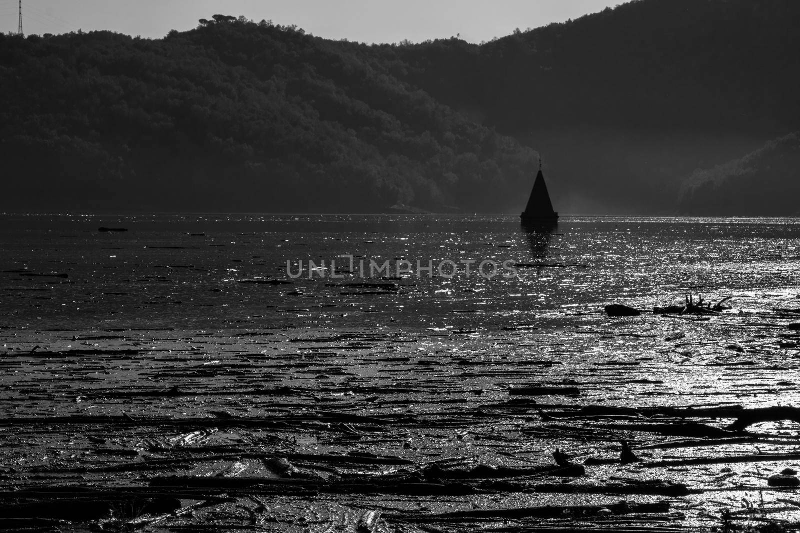 Black and white landscape showing some dirt and a flooded church in Sau swamp in Catalonia