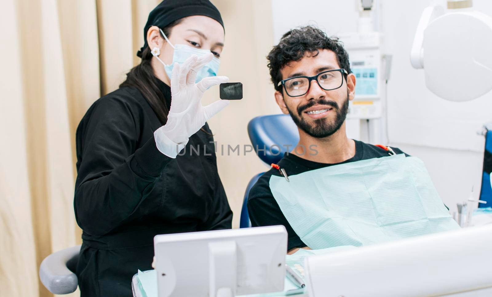 Dentist with patient showing him a periapical x-ray, View of dentist with patient reviewing dental x-ray. Dentist showing periapical x-ray to patient
