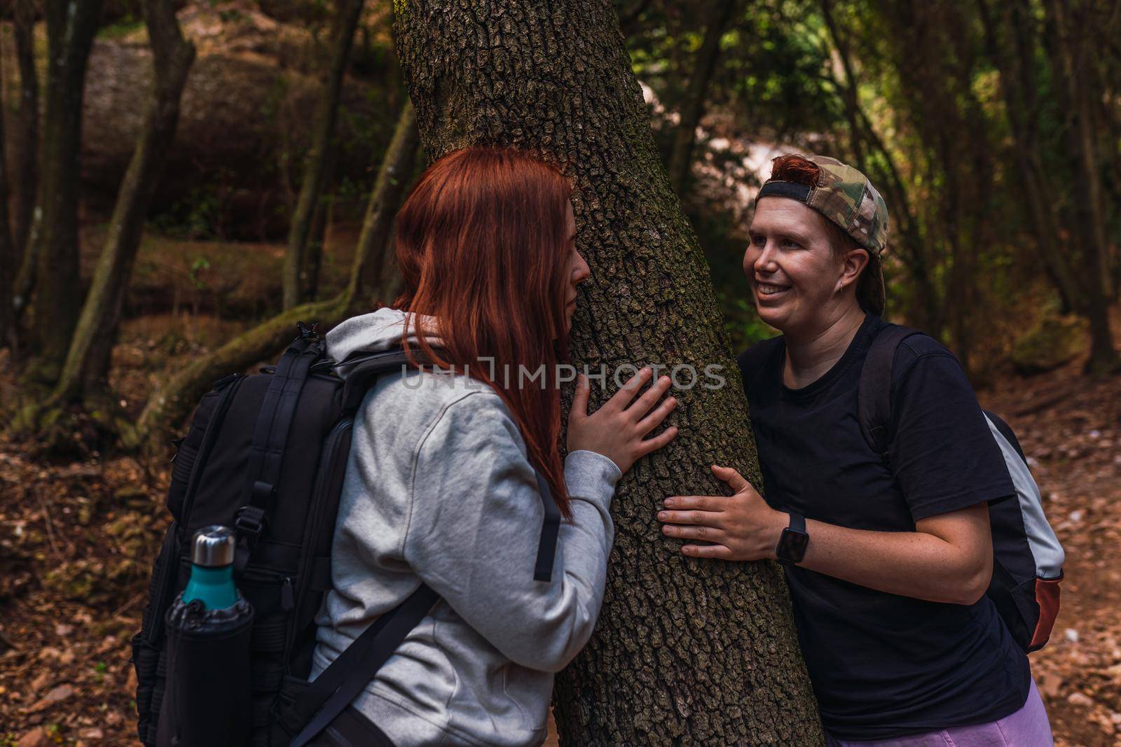 young women relaxing and enjoying themselves on a mountain trail. tourists hiking in nature. young people on holiday. hiking poles and mountaineer's backpack. natural and warm light. lush vegetation. hiking poles.