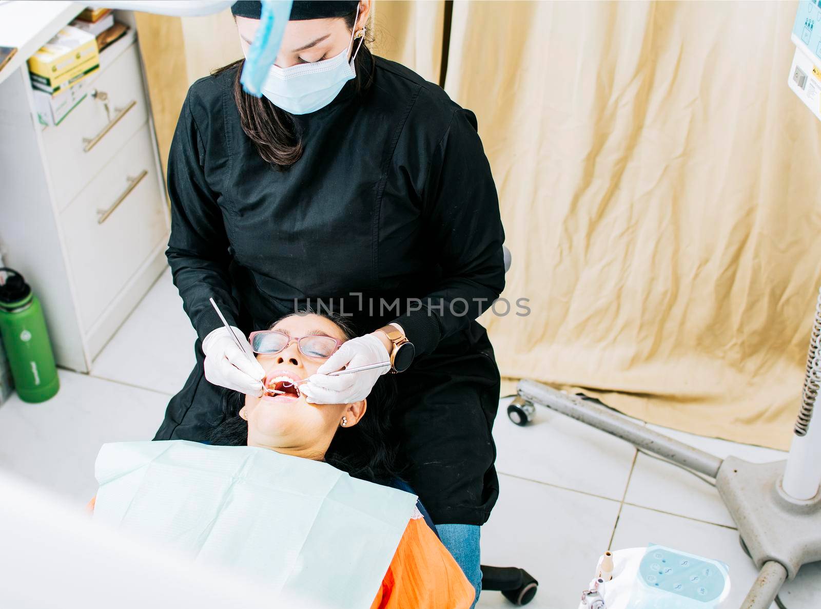 Woman dentist doing endodontics to woman patient; Dentist with patient lying down; Dentist examining mouth to patient; Dentist performing stomatology
