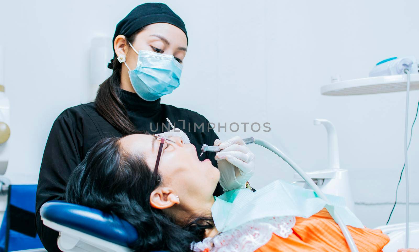 A dentist cleaning a patient's mouth, a dentist cleaning a patient's caries, a dentist cleaning a patient's mouth, The stomatologist cleaning a patient's teeth by isaiphoto