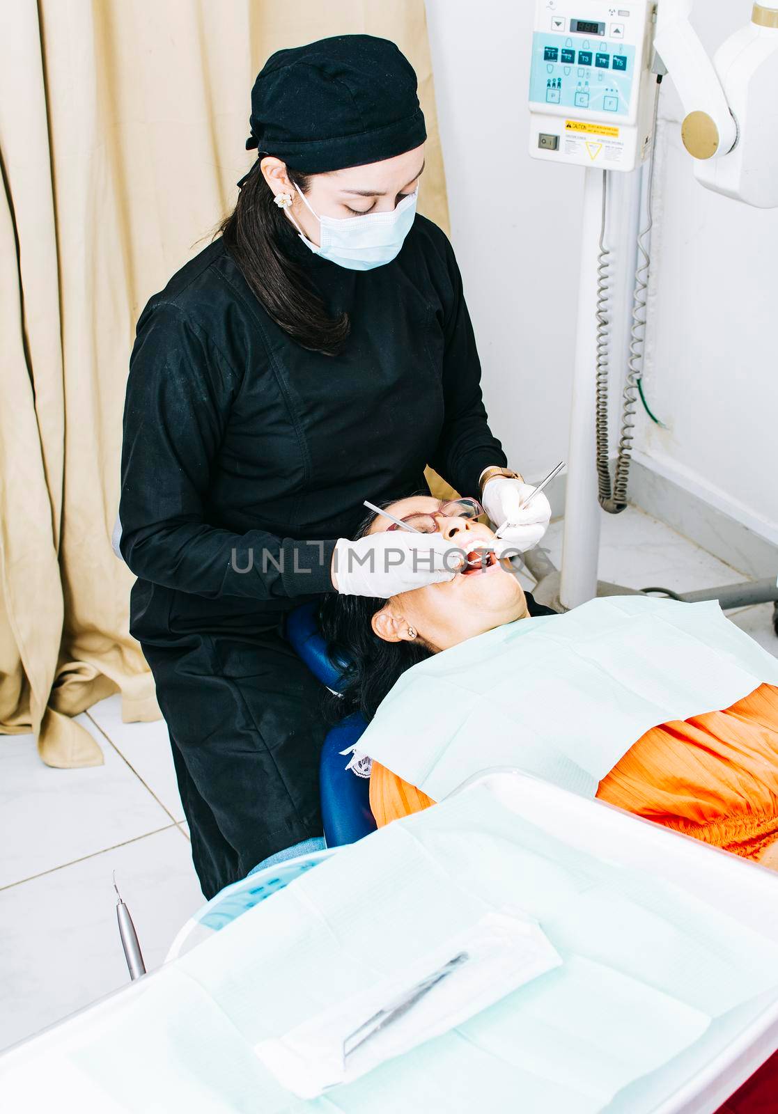Dentist with patient lying down, Dentist examining mouth to patient, Woman dentist doing endodontics to woman patient, Dentist performing stomatology by isaiphoto