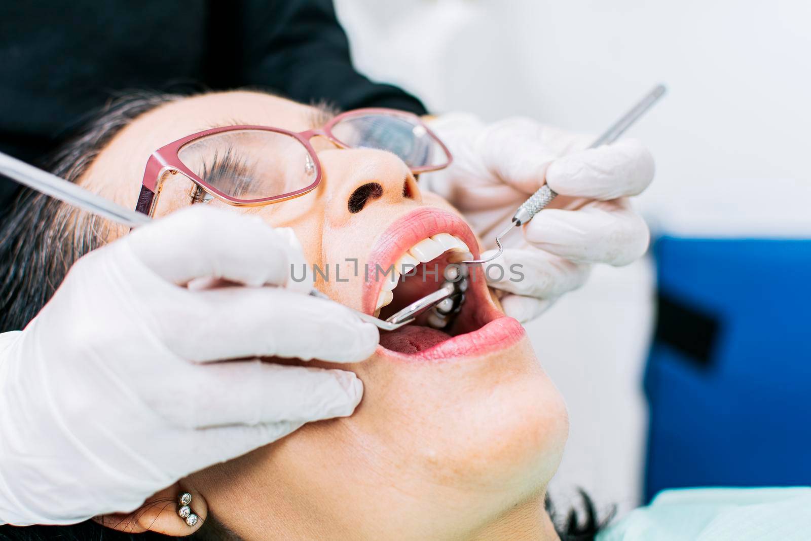 Female dentist checking a patient, close up of dentist with patient, dentist performing root canal on patient, dentist performing dental checkup by isaiphoto