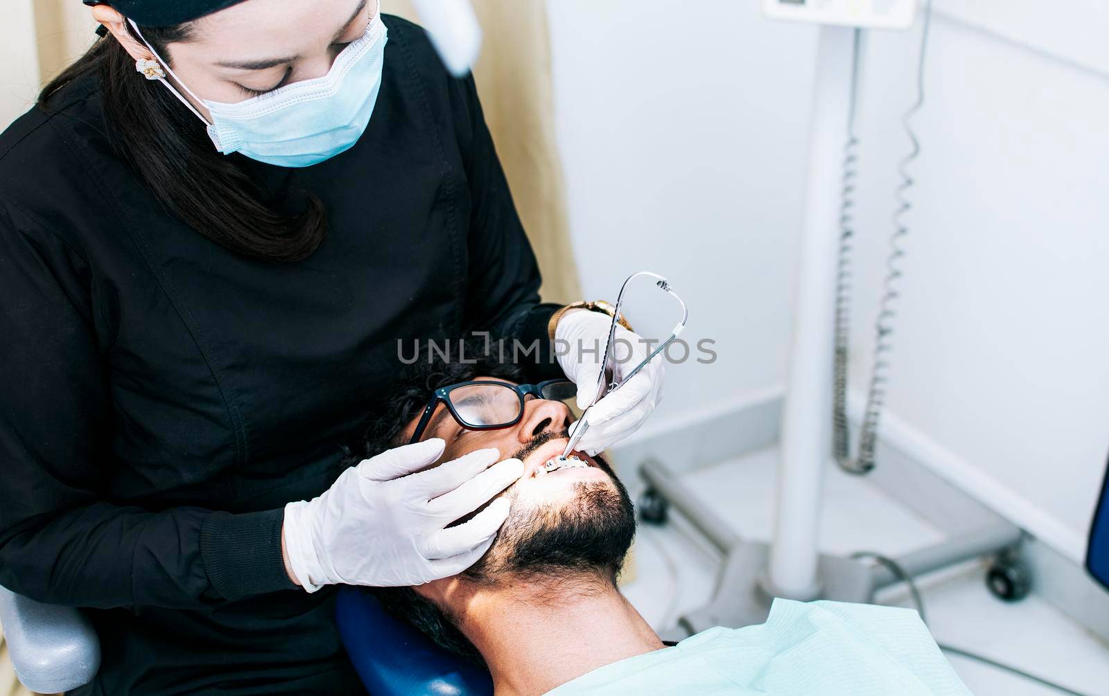 Dentist checking braces to patient, patient checked by dentist, Dentist performing dental checkup by isaiphoto
