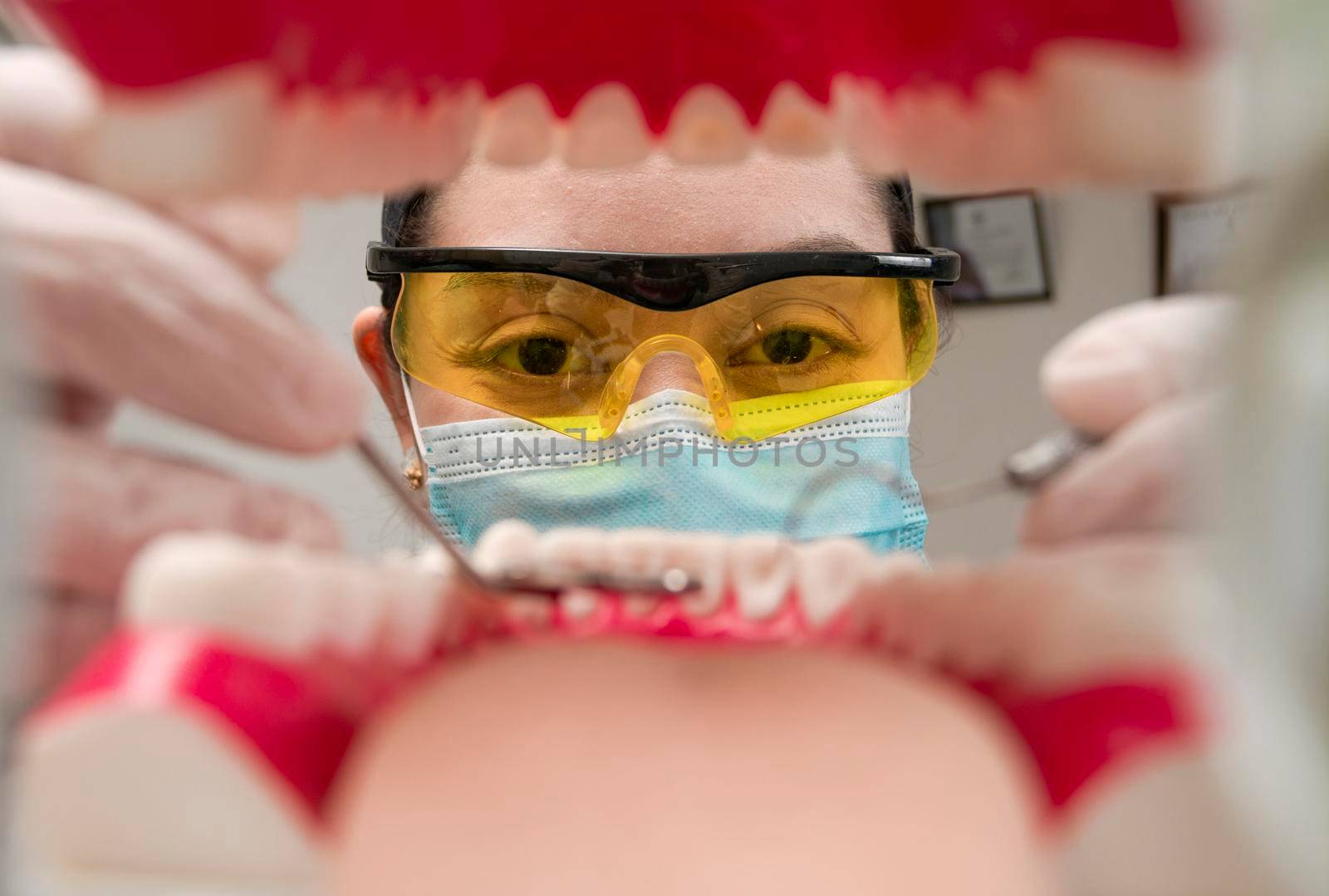 A dentist cleaning a mouth inside view, Inside view of a mouth checked by a dentist, a female dentist checking a patient. dentist checking a mouth, a dentist cleaning teeth. by isaiphoto