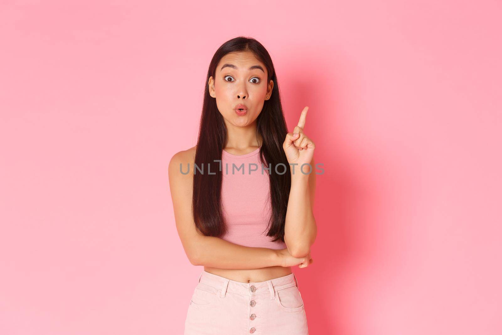 Lifestyle, beauty and women concept. Creative attractive asian girl in summer clothes have solution, raising index finger and saying her idea, think up great plan, standing pink background by Benzoix