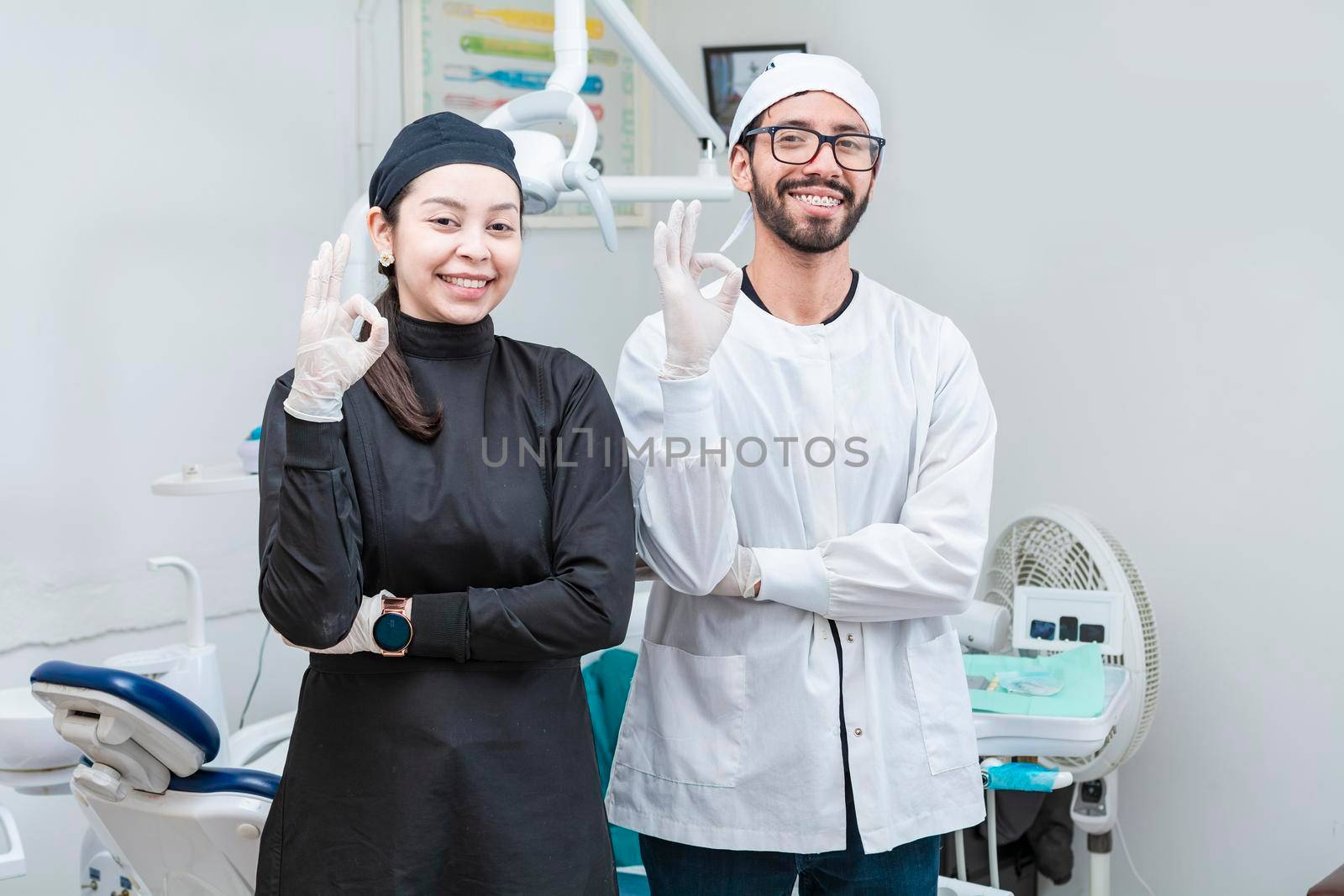 Portrait of dentist and her assistant in the office, female dentist and her assistant thumbs up, oral professionals portrait