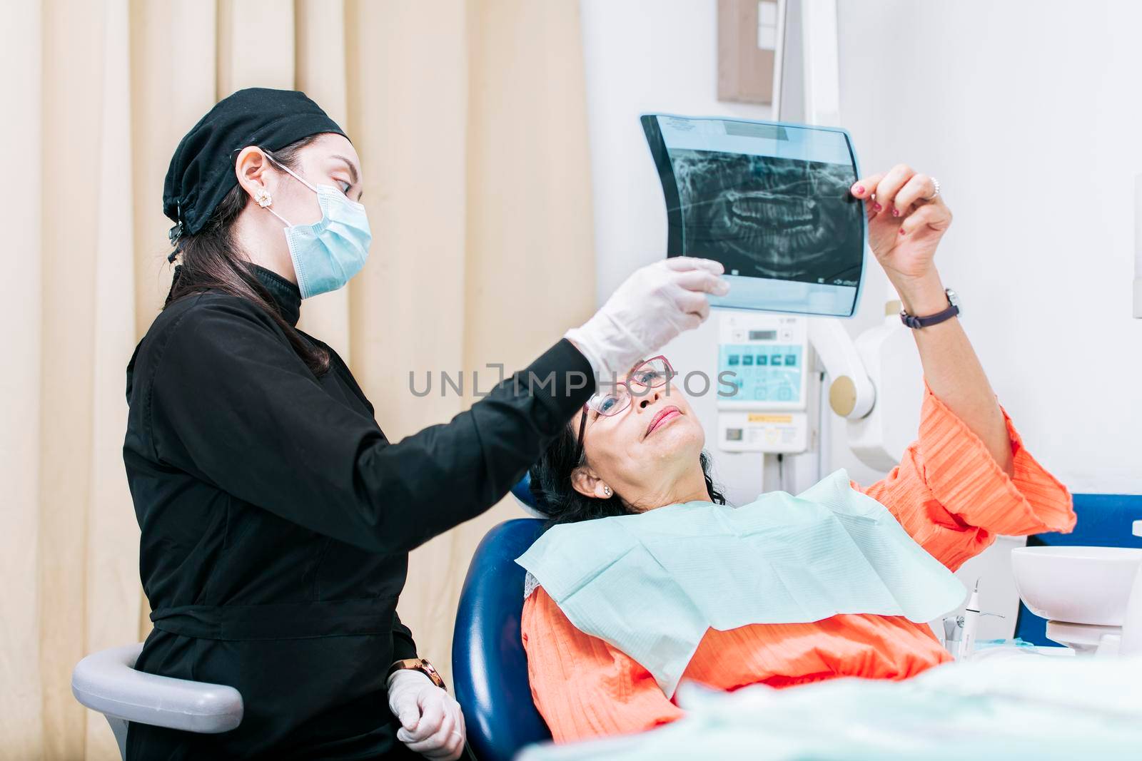 Dentist showing x-ray to patient, patient looking at x-ray with dentist, dental patient holding her x-ray, a dentist with x-ray examination by isaiphoto