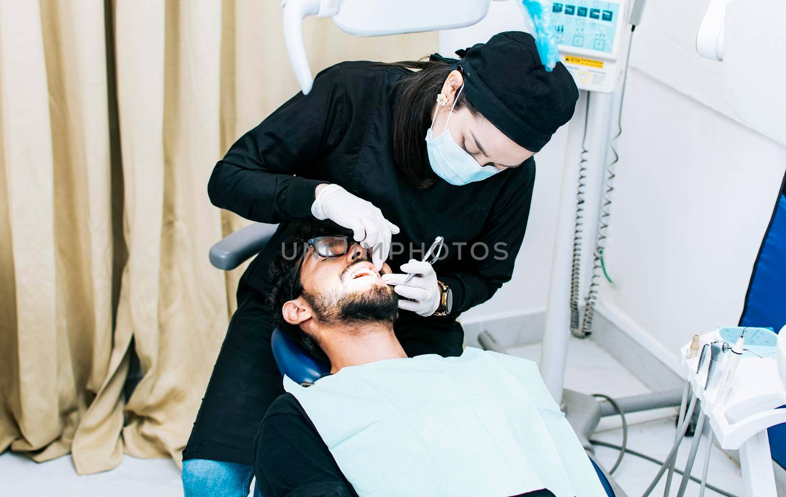 Dentist performing dental checkup, dentist checking braces to patient, patient checked by dentist