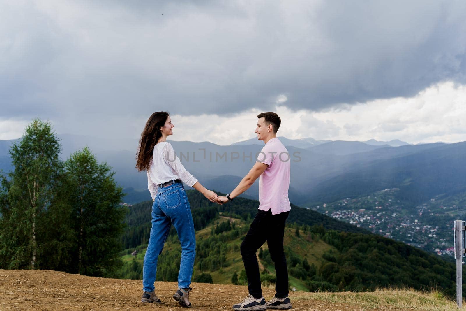 Couple looking to each other at the mountain hills before raining. Feeling freedom together in Karpathian mountains. Tourism travelling in Ukraine.