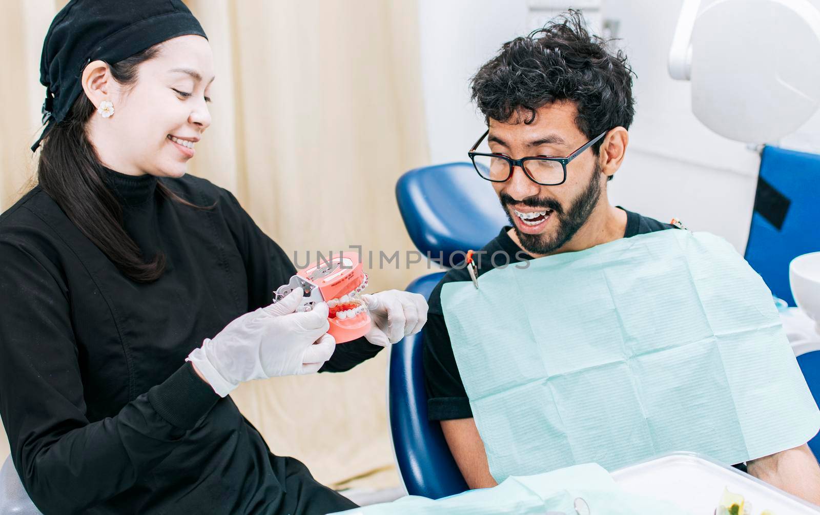 Dentist with patient showing a denture, dentist pointing out a denture to a patient, dentist explaining dental hygiene to a patient