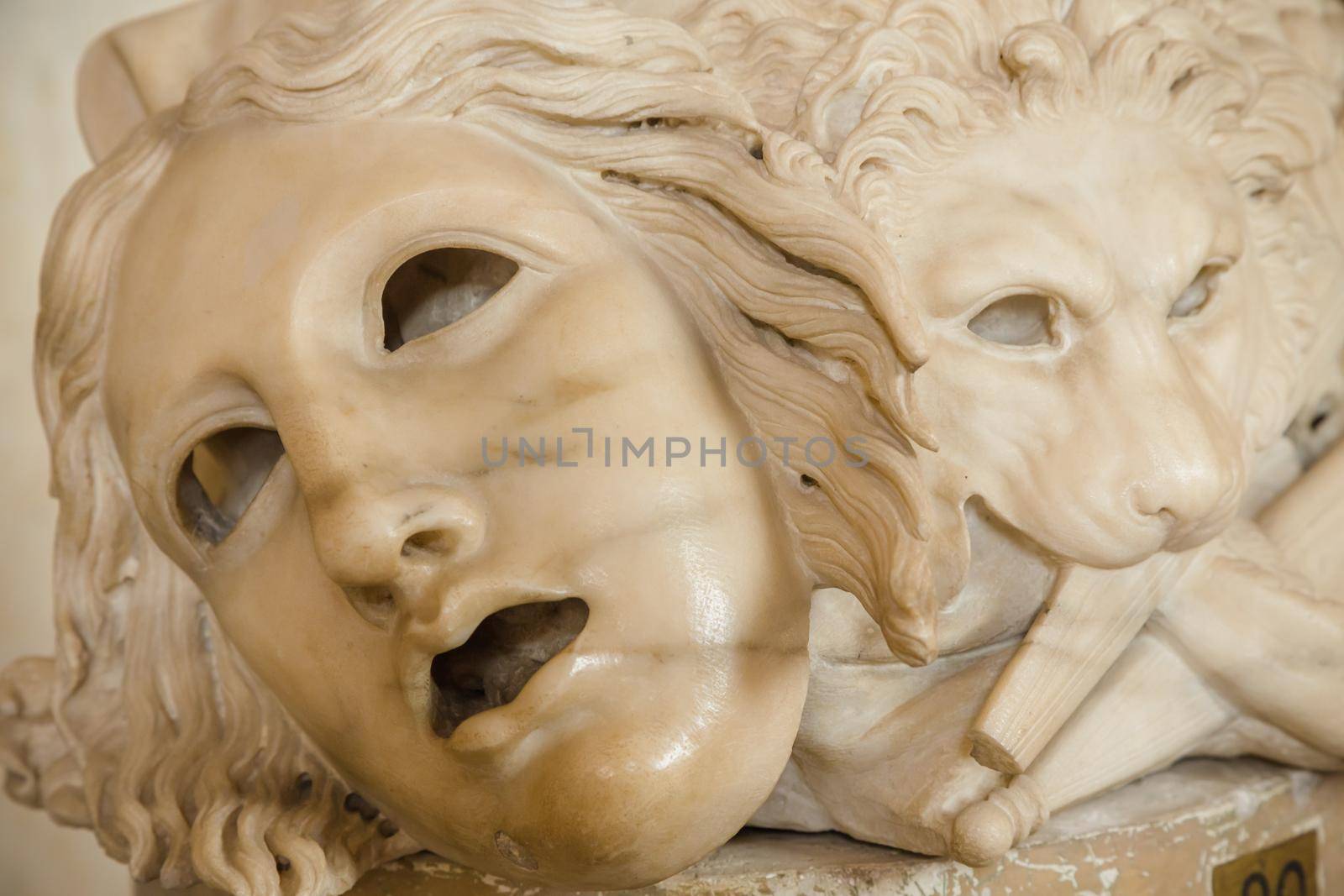 Ancient theatre mask, made of marble, located at the base of a Roman column in Rome - Italy