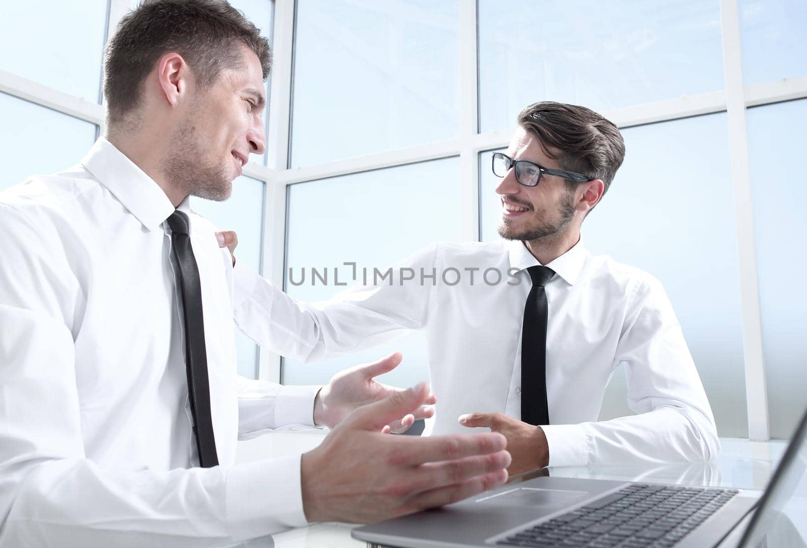 Two businessmen are sitting in the office and discussing the conclusion of a new deal