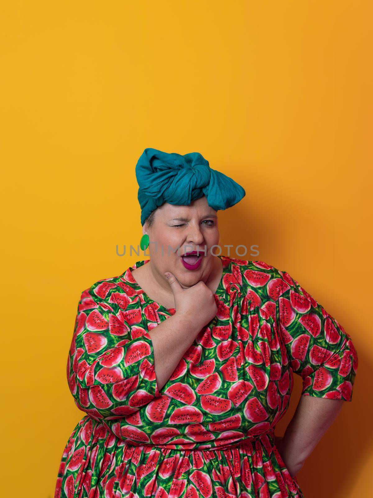 Funny plus size sexy model woman with trendy makeup, fashionable overweight blonde in colorful dress posing at the yellow background in studio. High quality photo