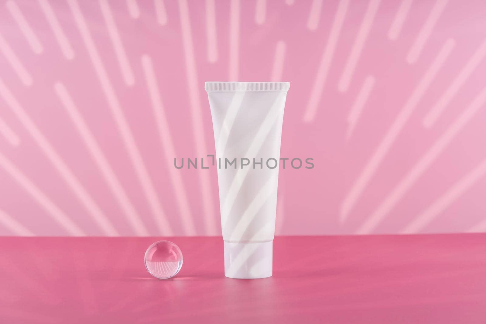 Unbranded cosmetic cream white plastic tube mockup on pink background with stylish props. Blank body and health care beauty product packaging. Moisturising hand creme bottle. Product presentation