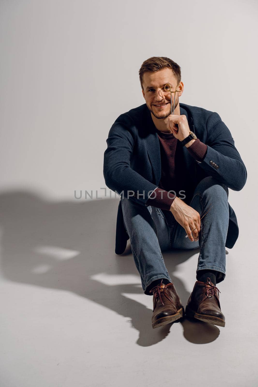 Doctor with surgical equipment needle and scissors. Handsome man weared casual business suit. Portrait of surgeon in studio