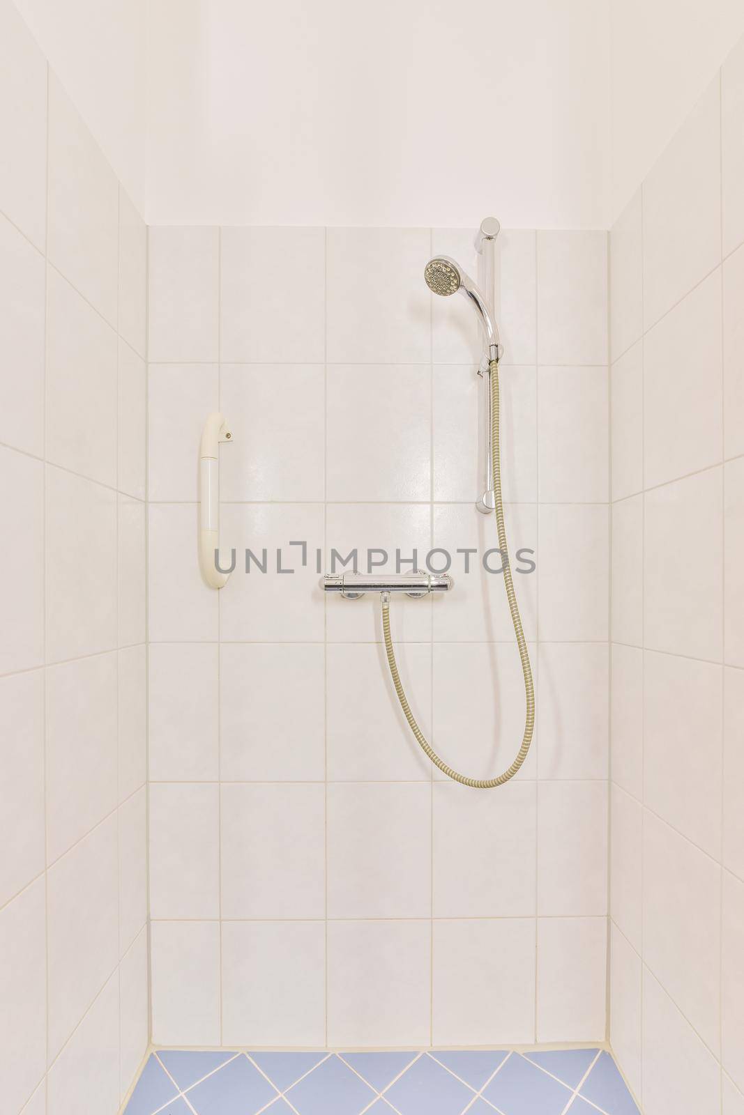 The interior of a bathroom with white and blue tiles and a shower cabin in a modern apartment