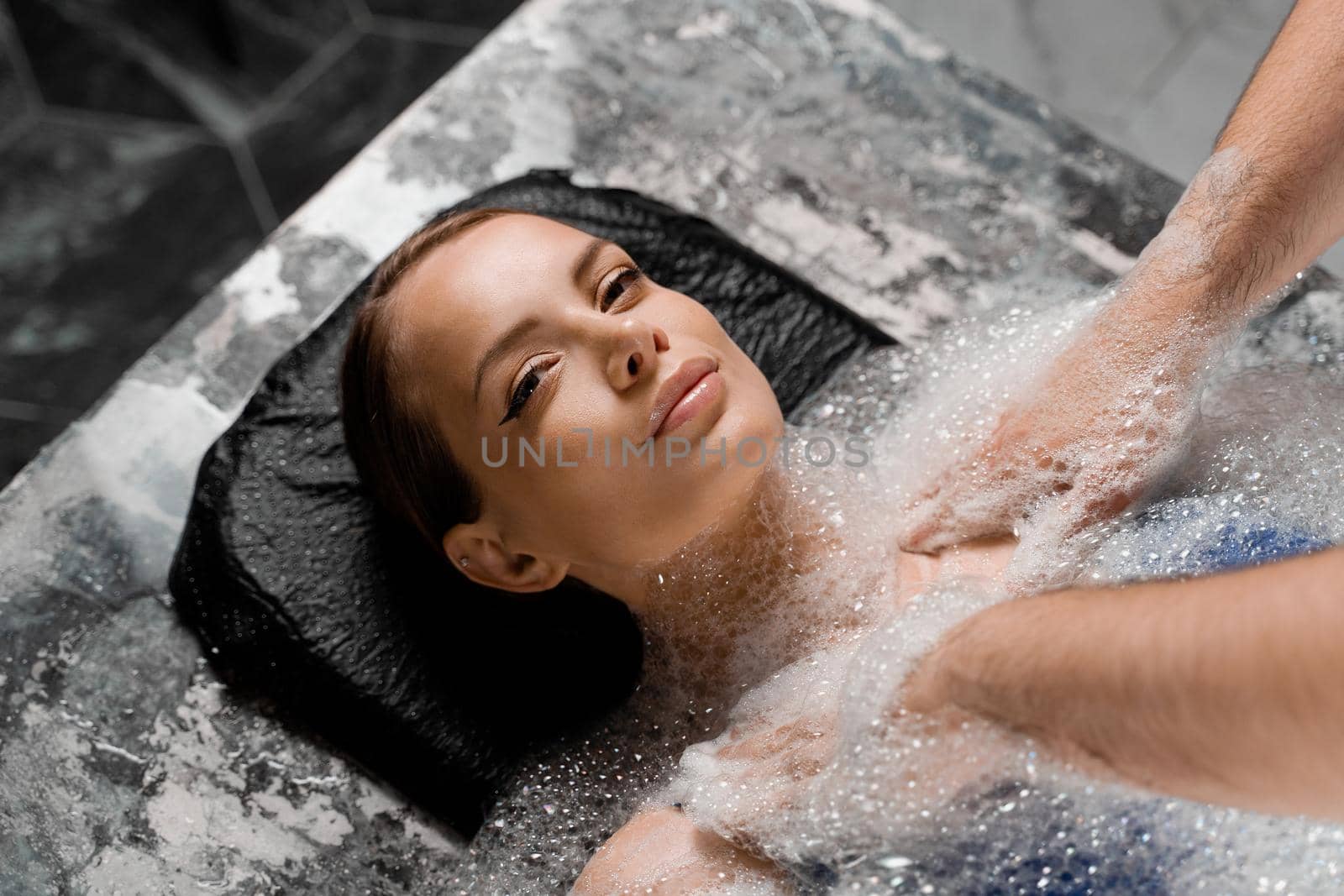 Close-up portrait of girl on foam peeling procedures in spa. Model is relaxing in Turkish hammam
