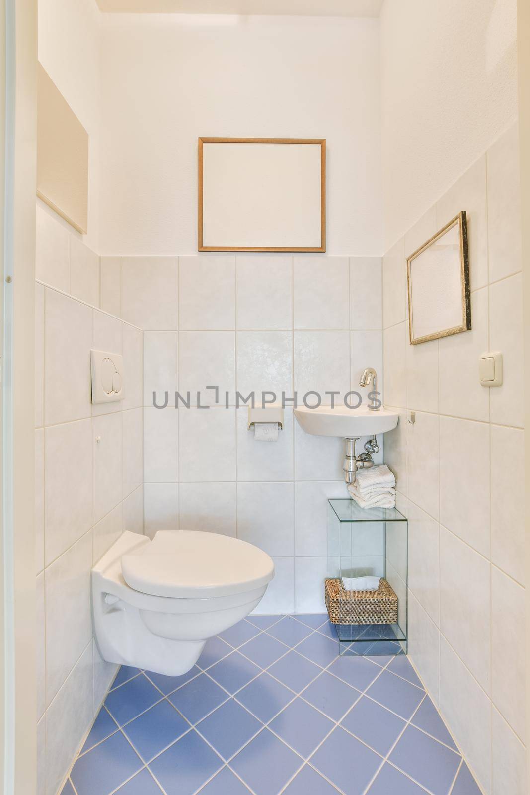 Bathroom interior with white and blue tiles and ceramic sink and hinged toilet in a modern apartment
