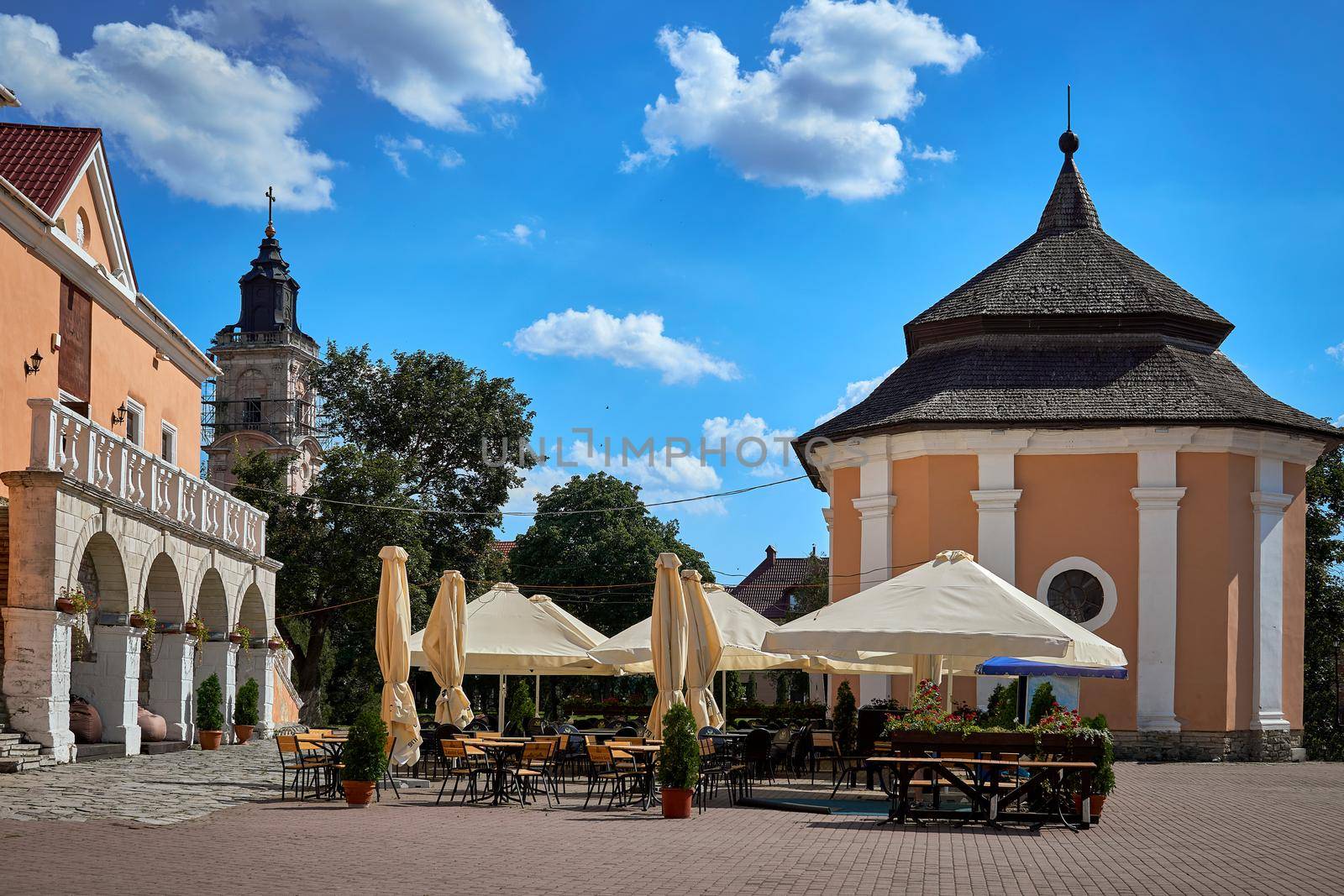 Summer open-air cafe with umbrellas and flowers on a medieval square by jovani68