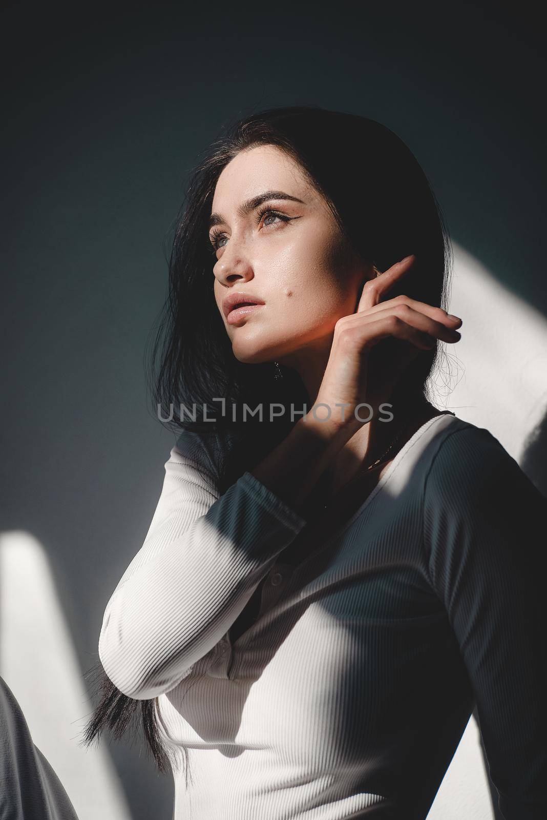 portrait of beautiful gentle woman in a white bodysuit posing in the sunshine. Black long hair. sensuality and tenderness.