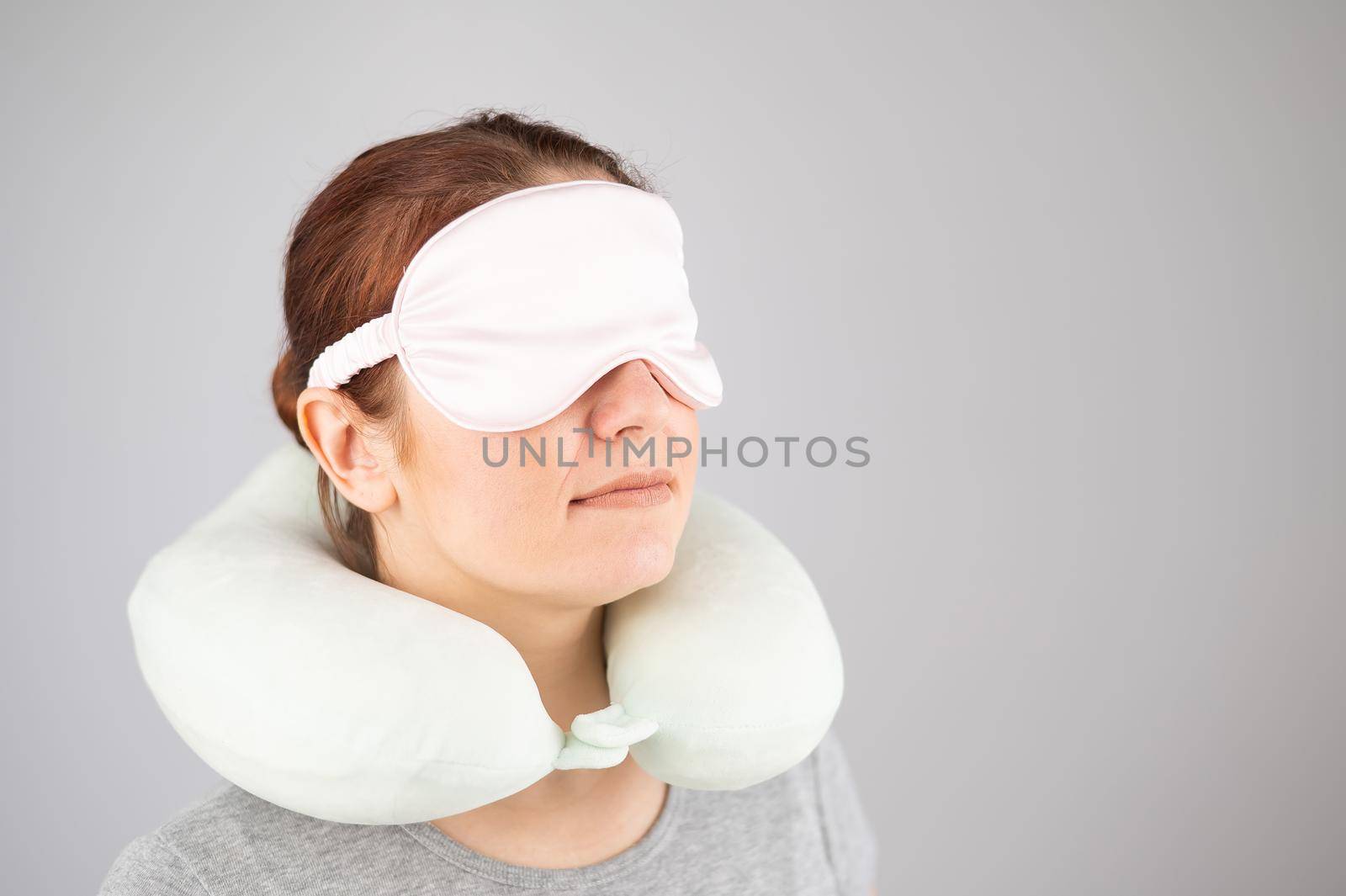 Caucasian woman with travel pillow and sleeping mask isolated on white background