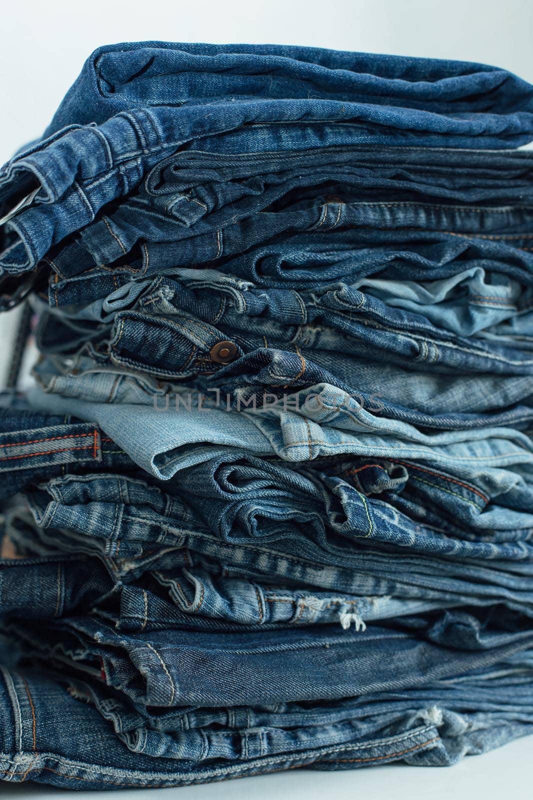 Stack of a stack of old jeans various shades of blue jeans. Denim jeans texture. Denim background texture for design. Canvas denim texture. Blue denim background.