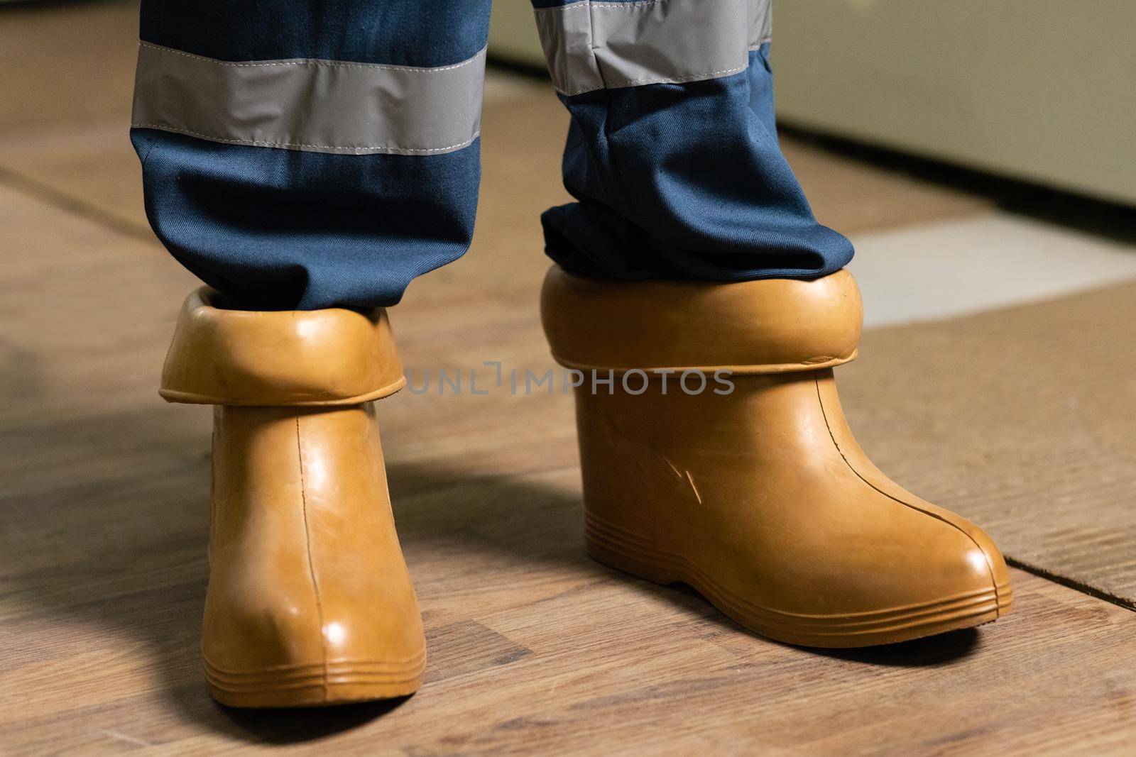 Electrician wears rubber boots for safety to avoid electric shock. Concept of electric power station development. Electrical technician is putting on special protective shoes in power station.