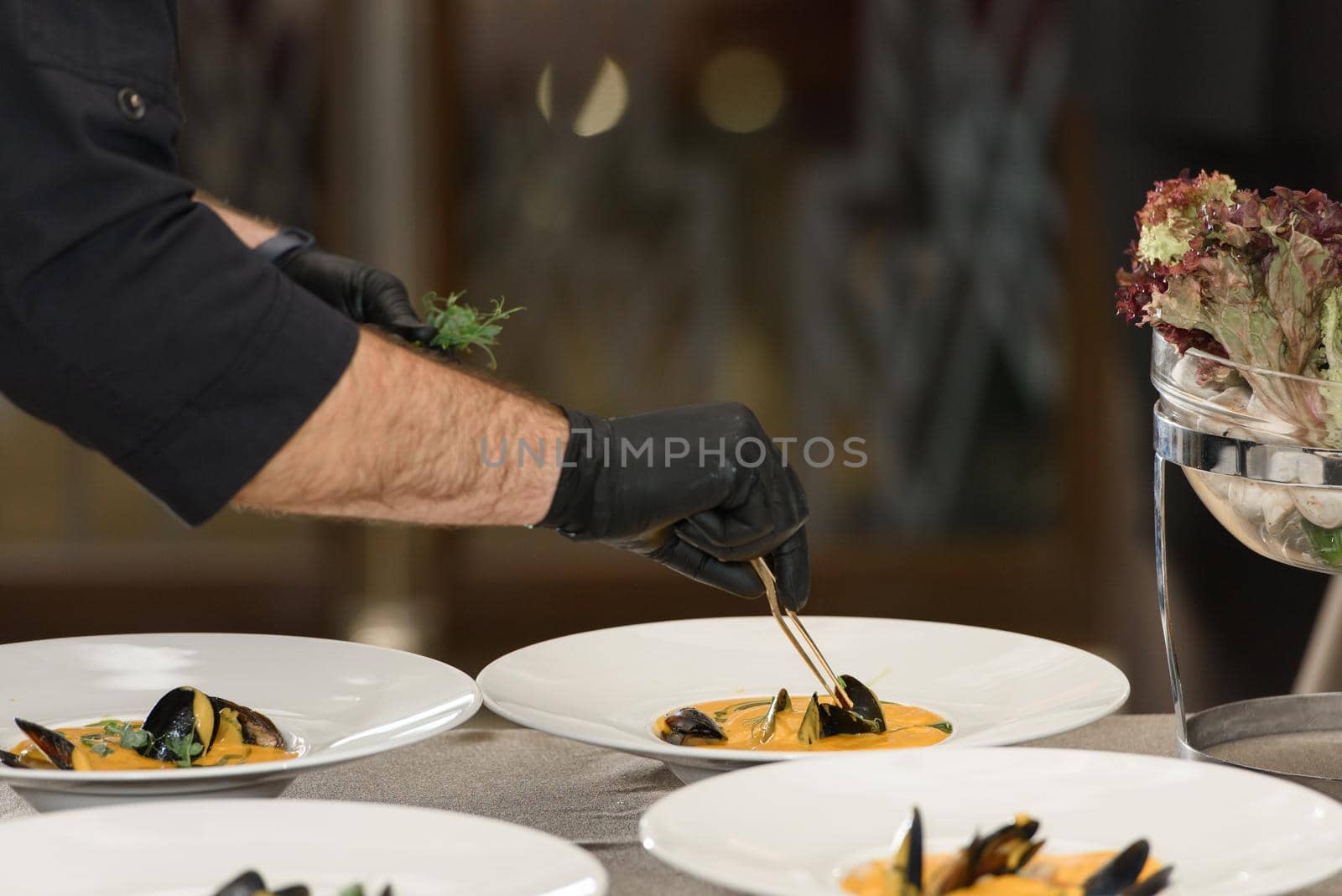 chef prepares set of carrot cream soup with seafood in a restaurant