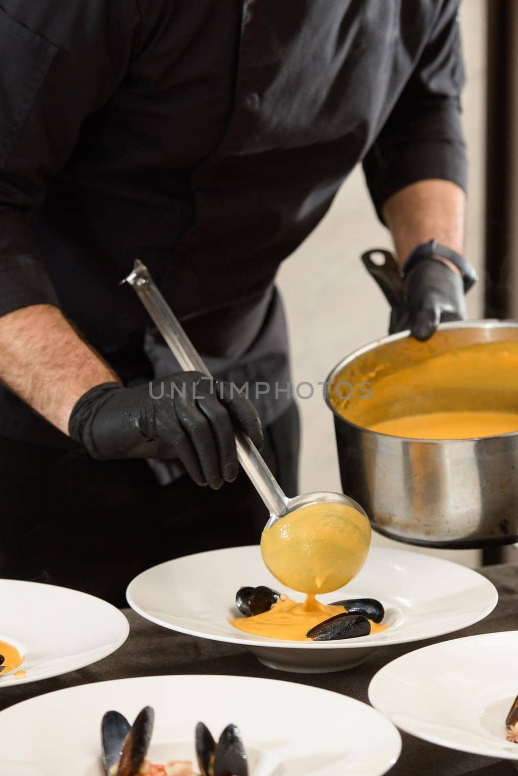 chef prepares set of carrot cream soup with seafood in a restaurant