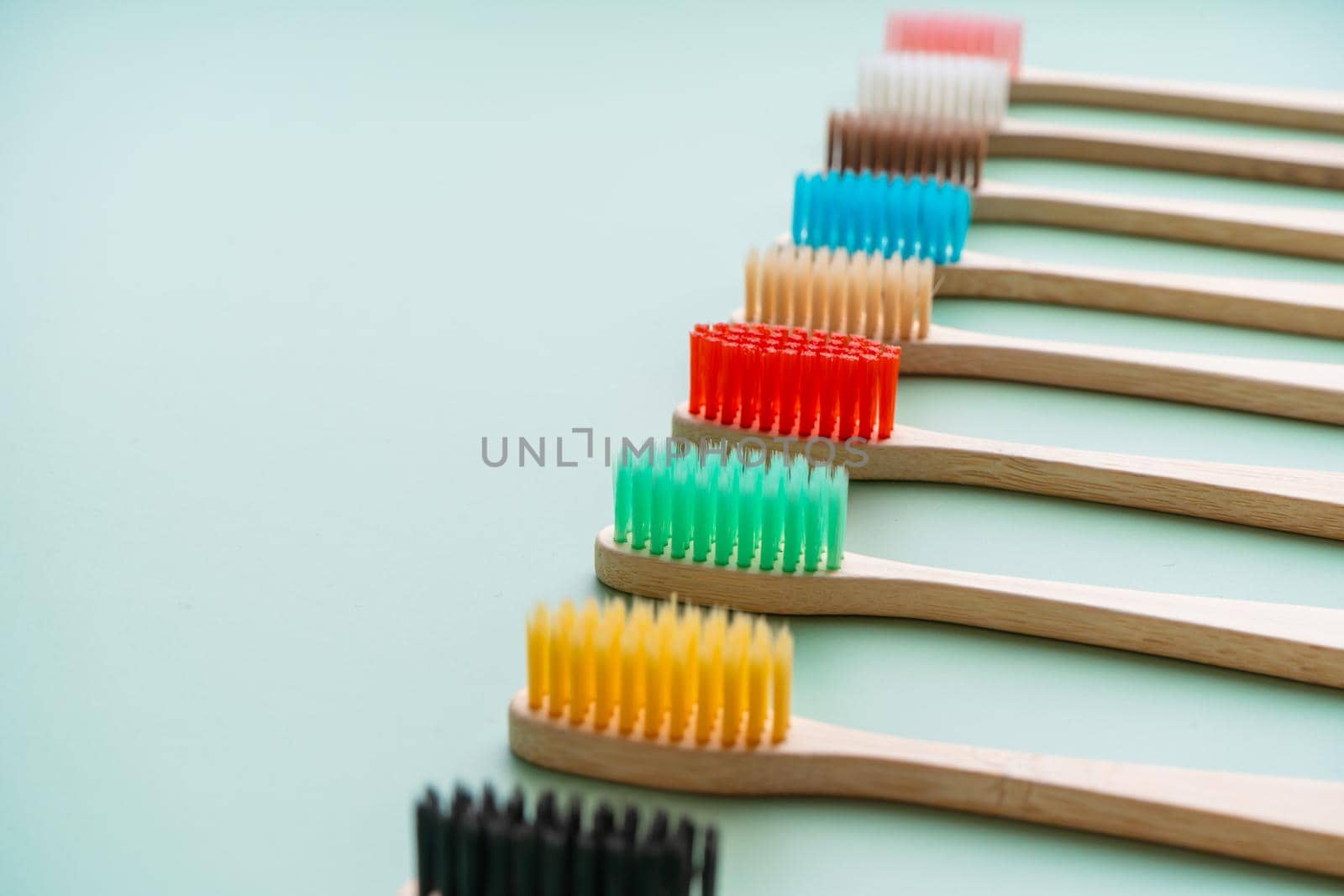 A set of Eco-friendly antibacterial toothbrushes made of bamboo wood on a light green background. Environmental care trends.