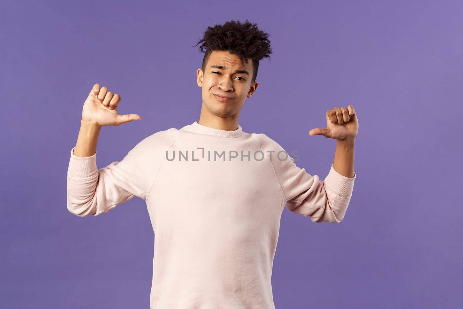 Portrait of boastful handsome young male student with dreads, bragging about how he workout in gym, show-off, pointing at himself and smirk self-assured, standing purple background.