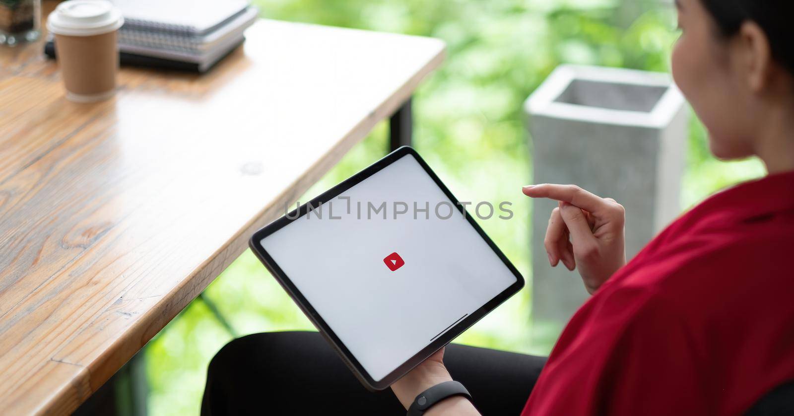CHIANG MAI, THAILAND - AUG 01, 2021 : Woman hand holding and is pressing the Youtube screen on apple digital tablet, YouTube is the popular online video-sharing website by nateemee