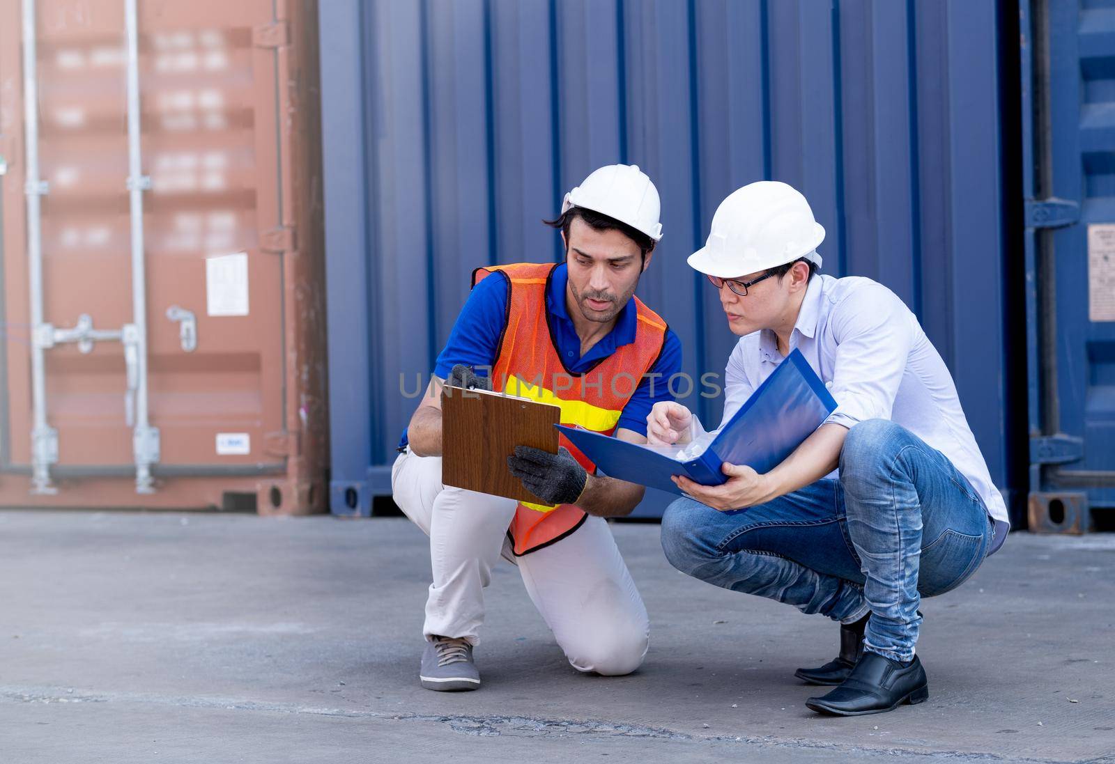 Foreman and container worker sit and discuss together about data in their document. by nrradmin