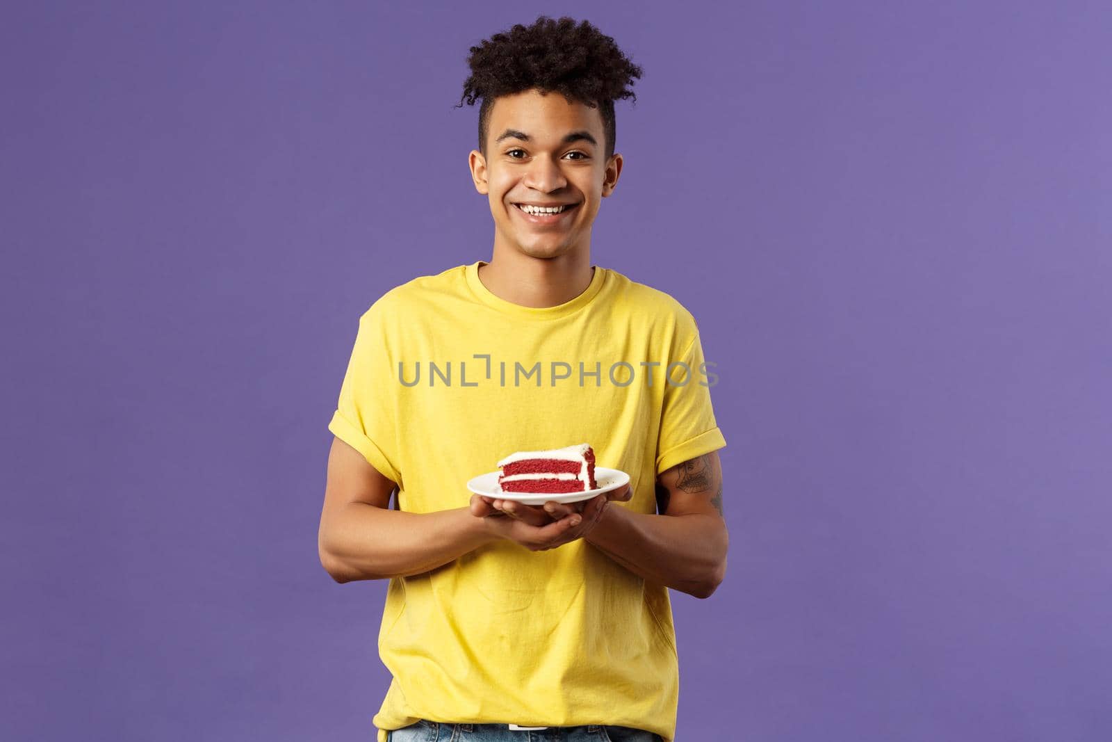 Celebration, party and holidays concept. Portrait of handsome young smiling man, feeling happy likes eating desserts, ordered delivery from local cafe to have some delicious cake, purple background by Benzoix