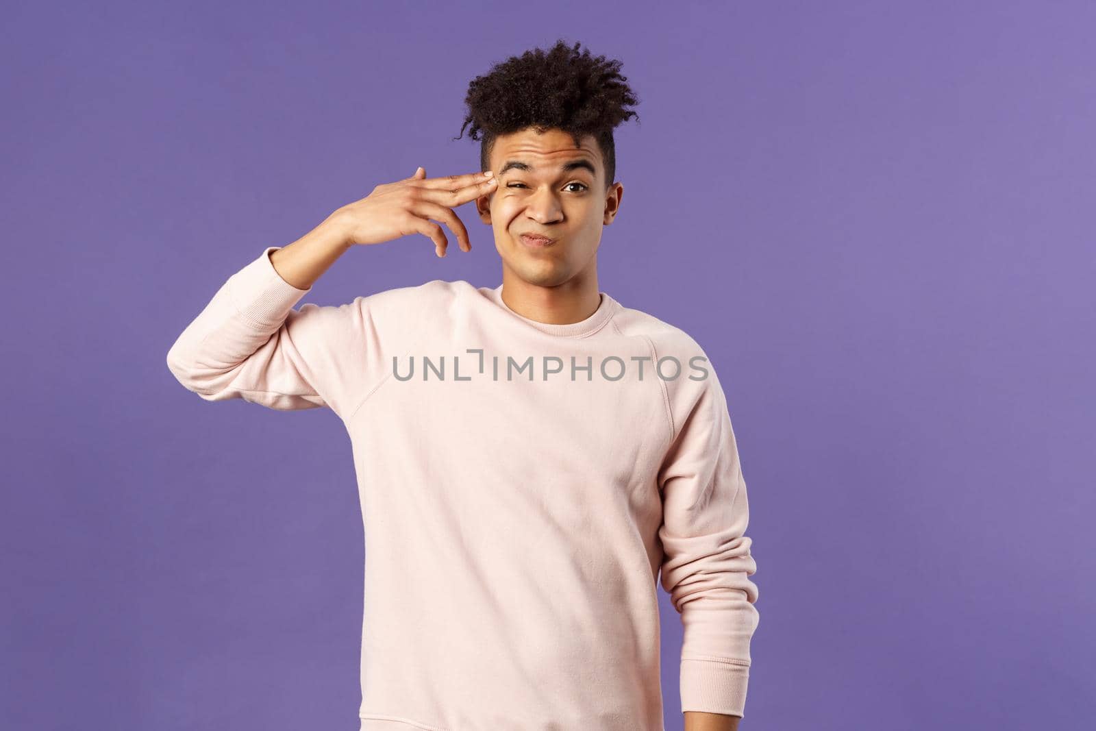 Portrait of young teenage guy, hispanic male student losing his mind at home lockdown, pointing at temple with finger gun and grimacing as shooting himself from boredom or annoyance by Benzoix