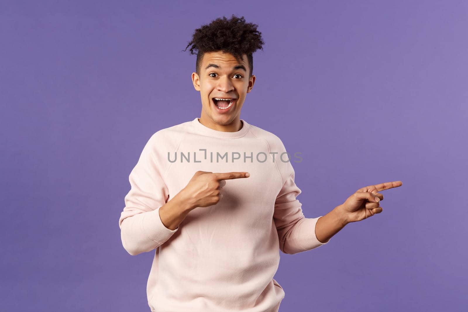 Portrait of enthusiastic lively hipster male 25s, pointing fingers right inviting join courses, sign up for awesome deal, best delivery service or online shop, look amused and happy camera.