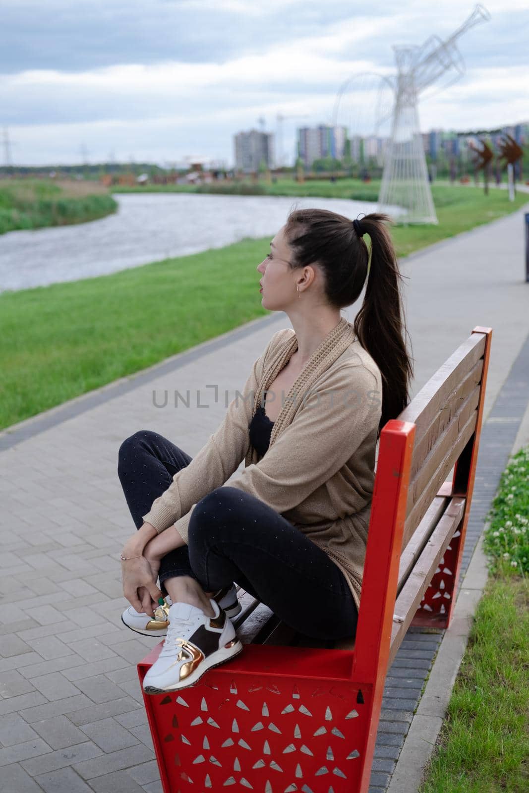 portrait of brunette woman with ponyrail sitting on a bench in park. nature lovers, attractive girl. by oliavesna