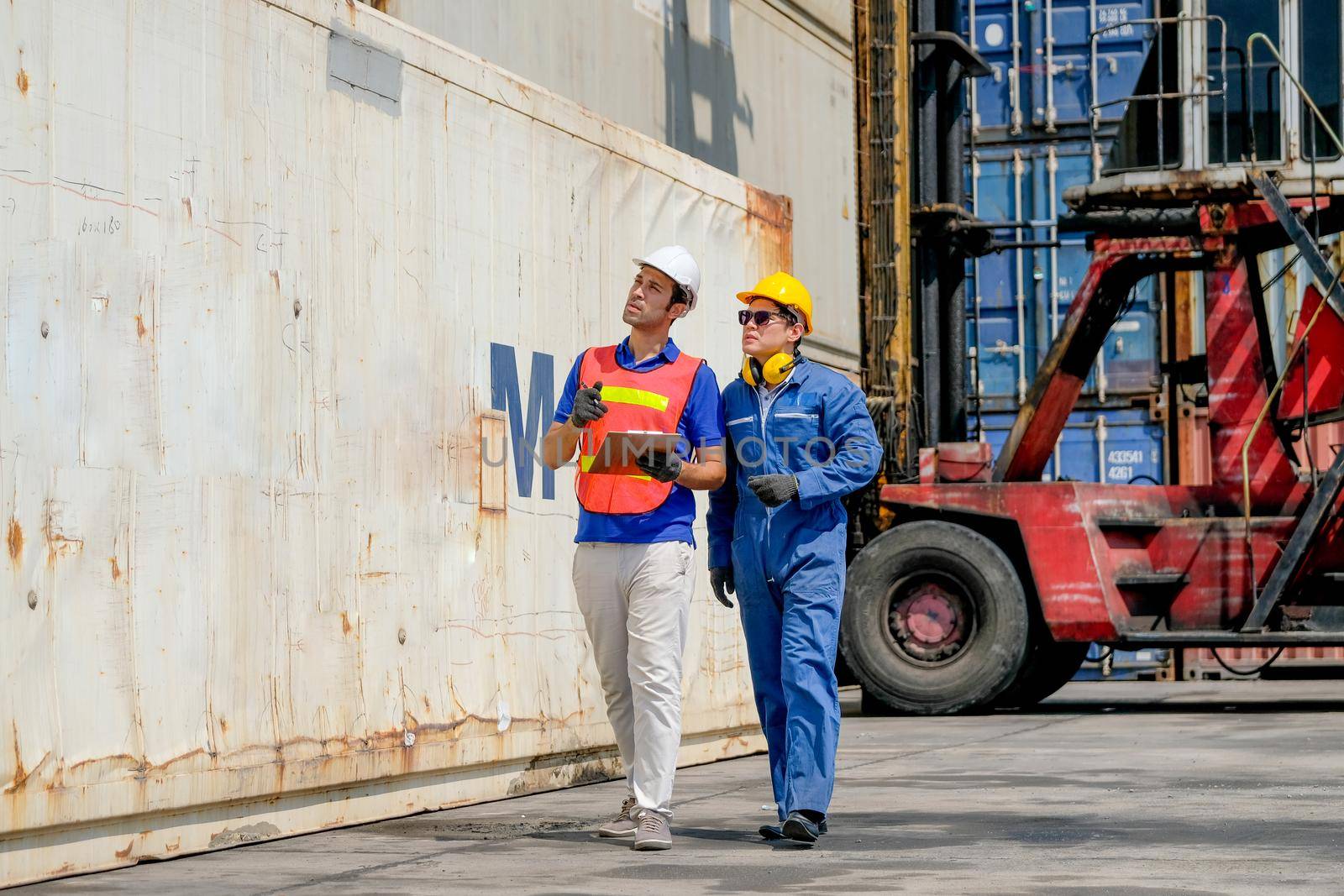 Technician and engineer work together for checking quality and product in cargo container shipping area.