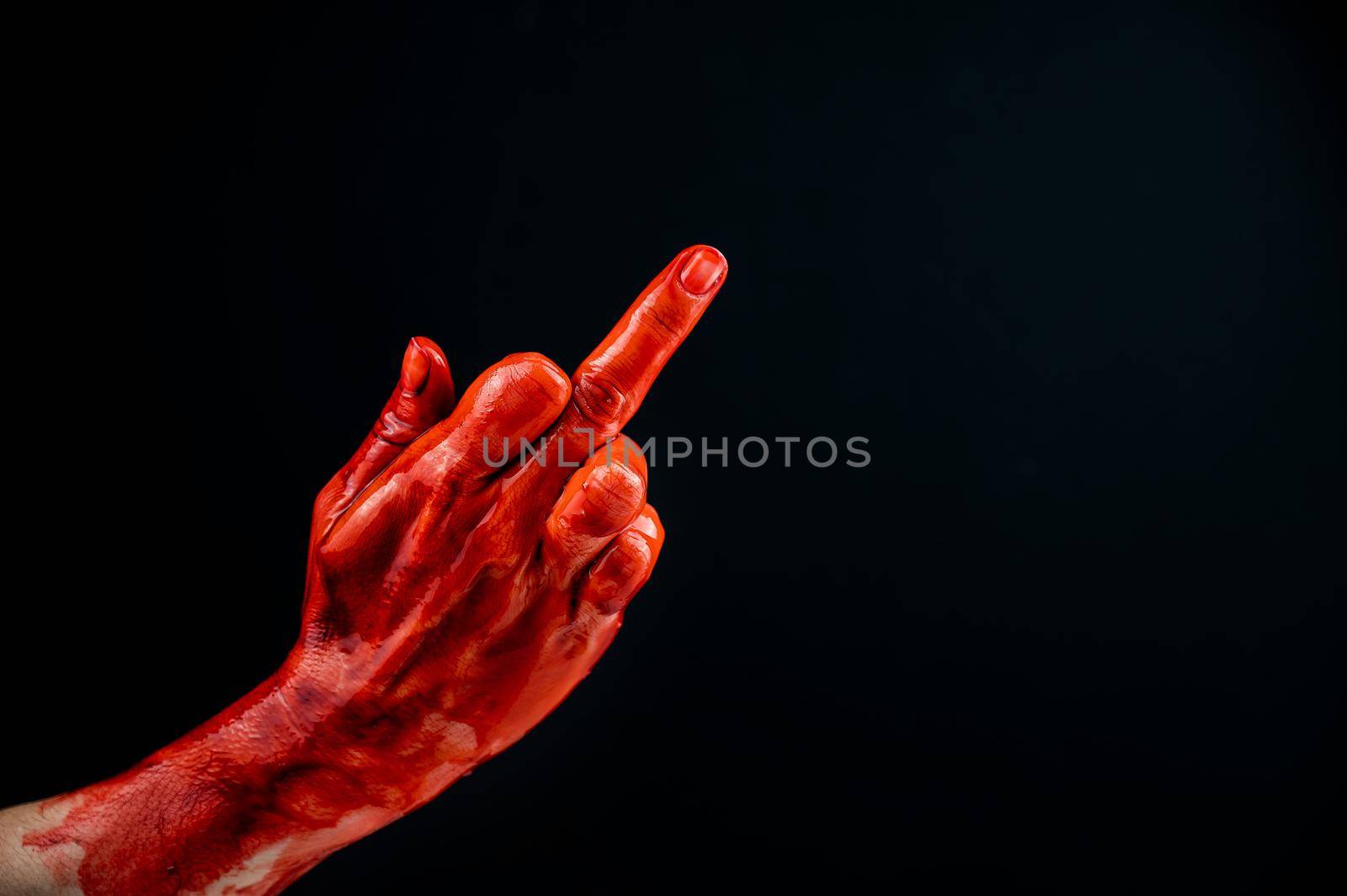 Female hand stained with blood shows the middle finger on a black background