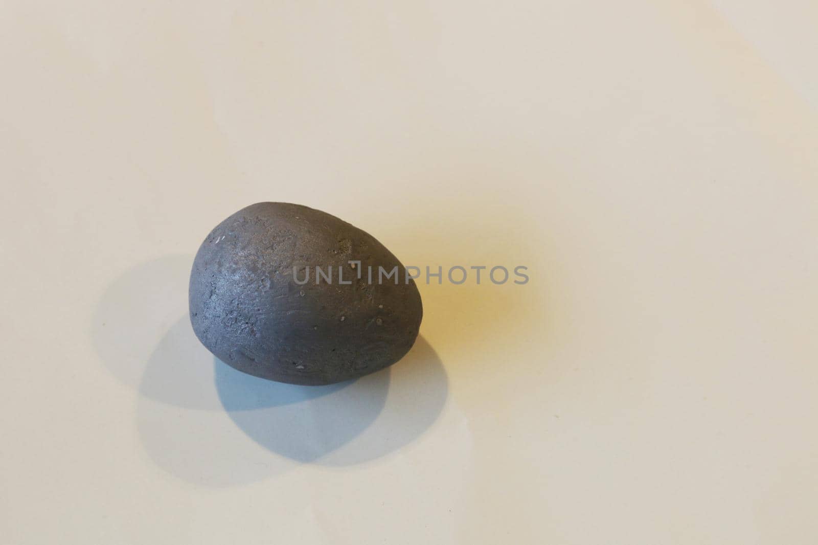 Artificial egg covered in gray primer. Decorative gray egg on light background with shadows.