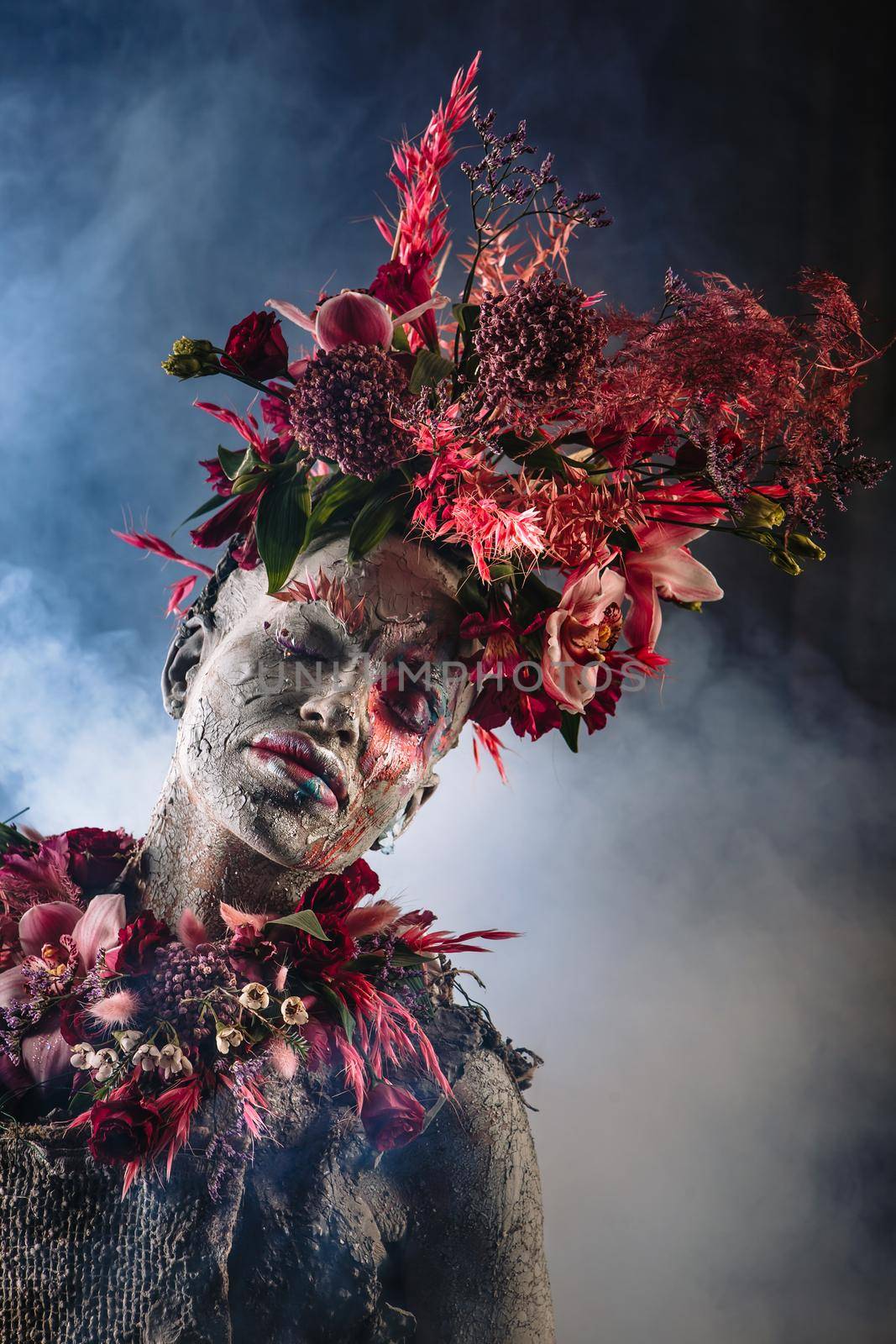 A girl smeared with clay. The model has a headdress made of flowers.