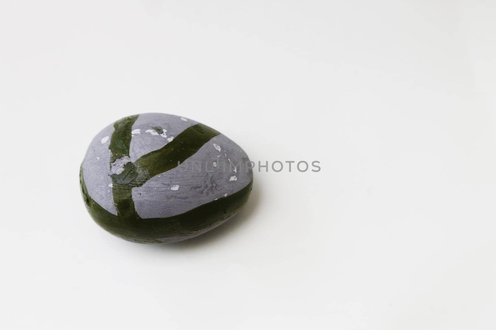 Stone decorative egg of gray color with stripes. Gray egg with a green pattern on a light background.....